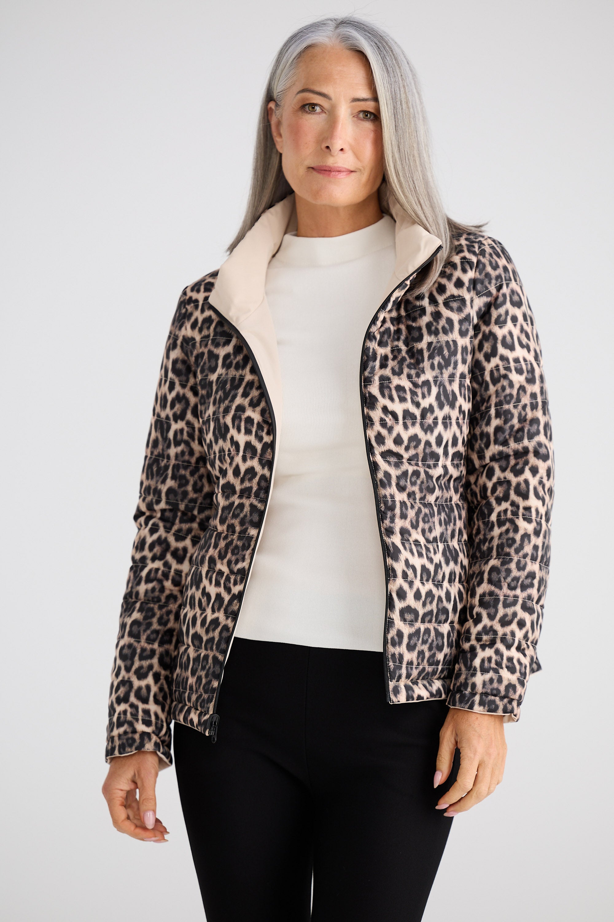 Woman wearing a leopard print jacket over a white shirt on a plain background
