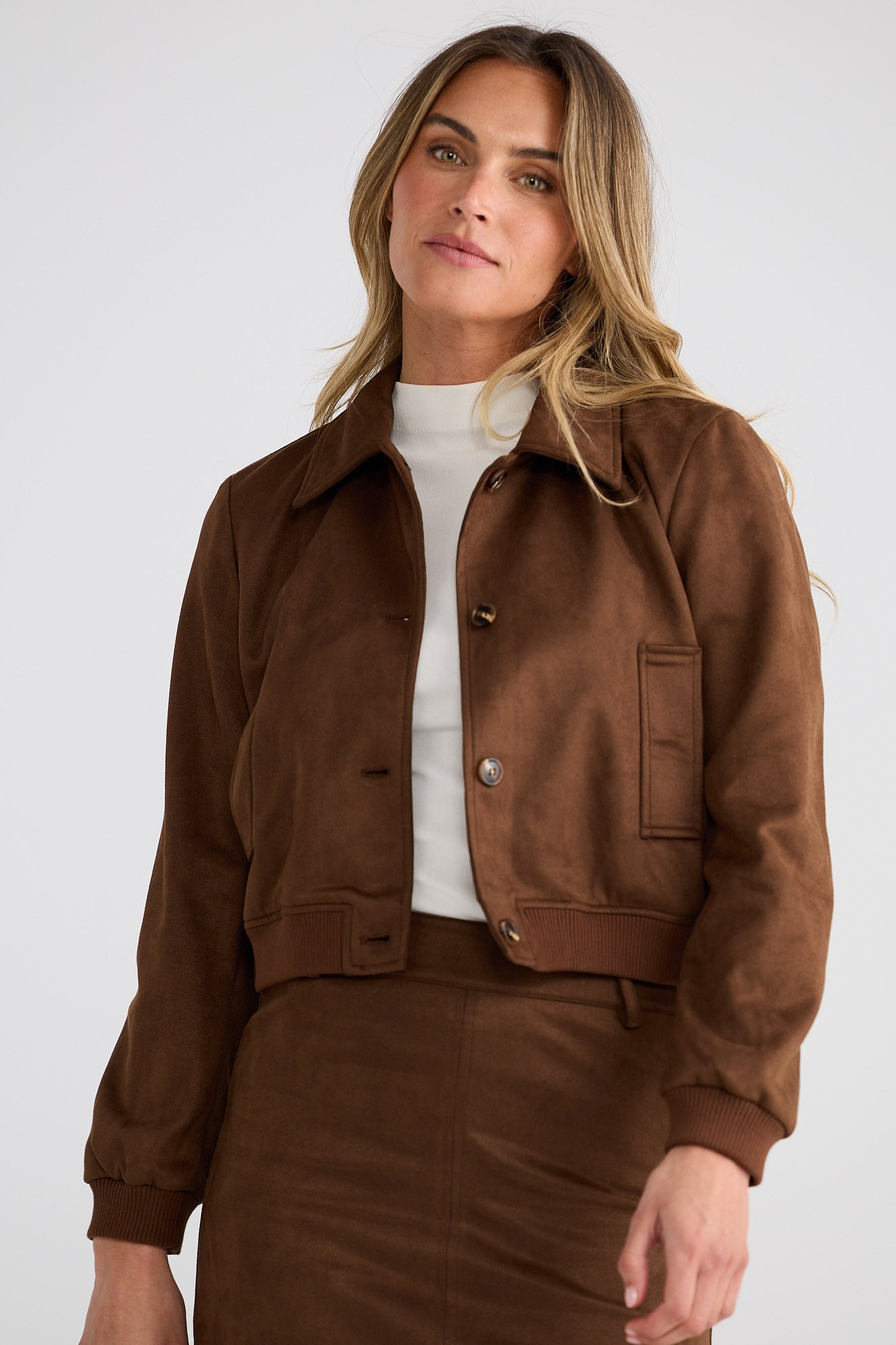 Woman wearing a brown jacket and skirt set on a white background