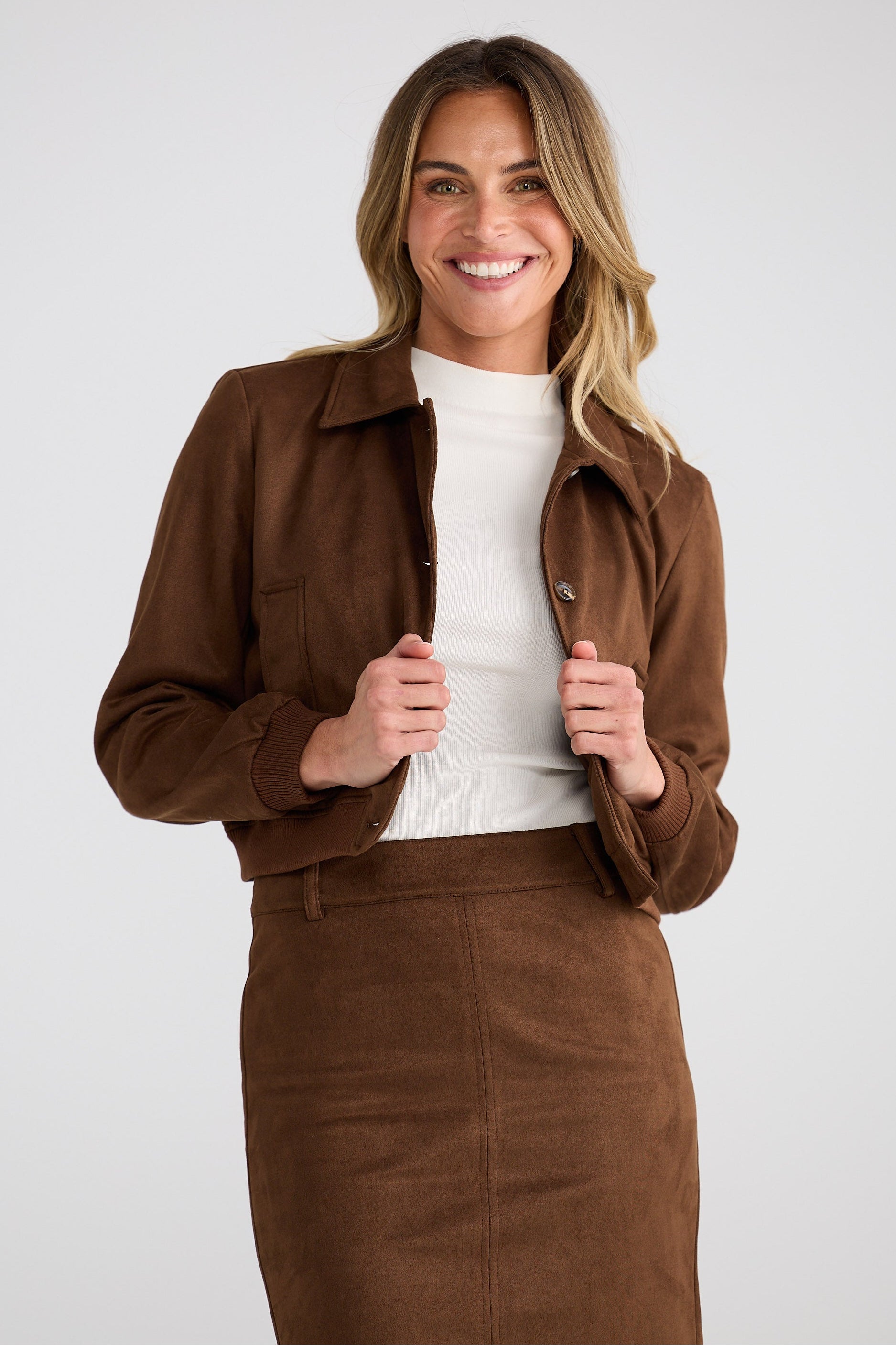 Woman wearing a brown suede jacket and skirt set on a white background