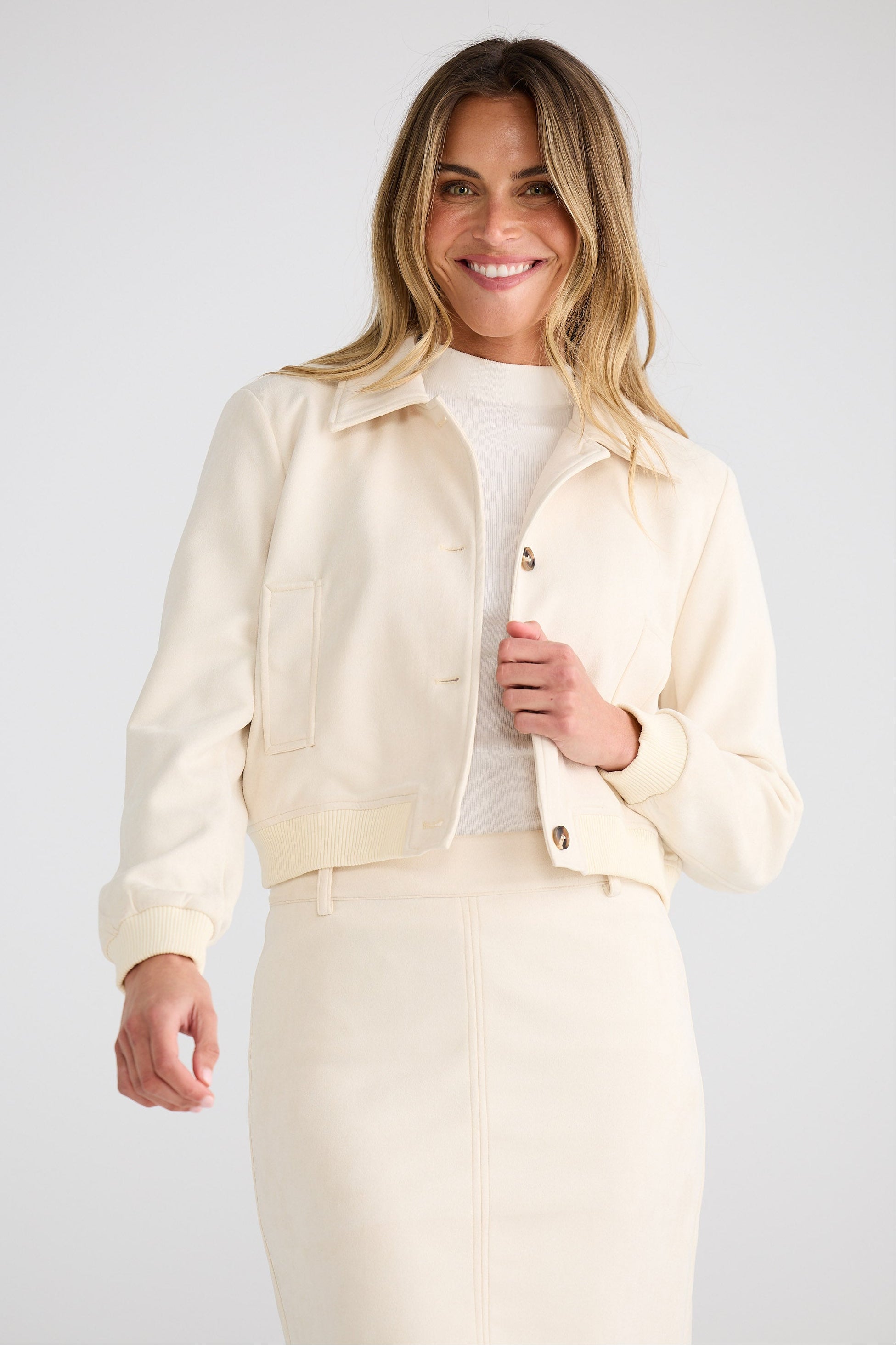 Woman wearing a cream-colored outfit against a white background