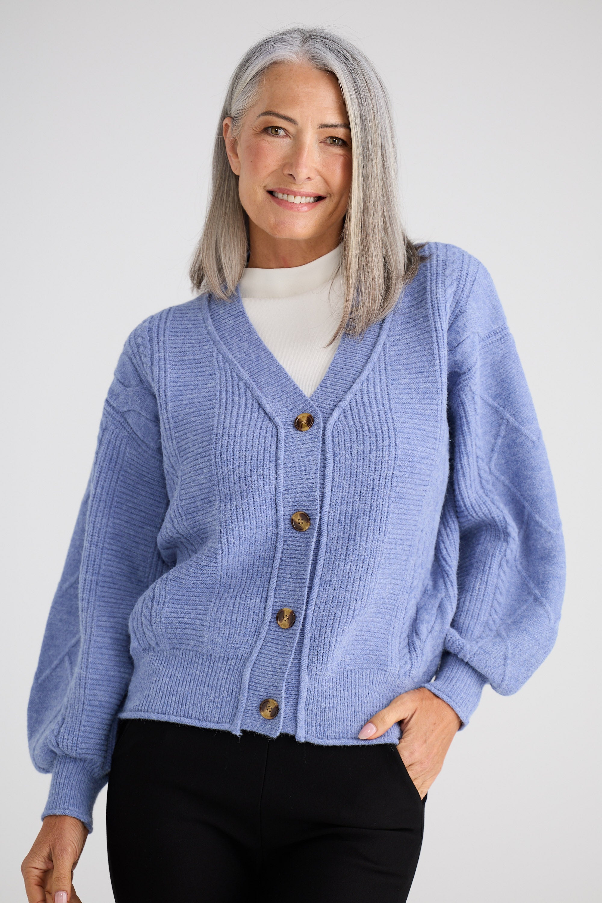 Woman wearing a blue cardigan with a white background
