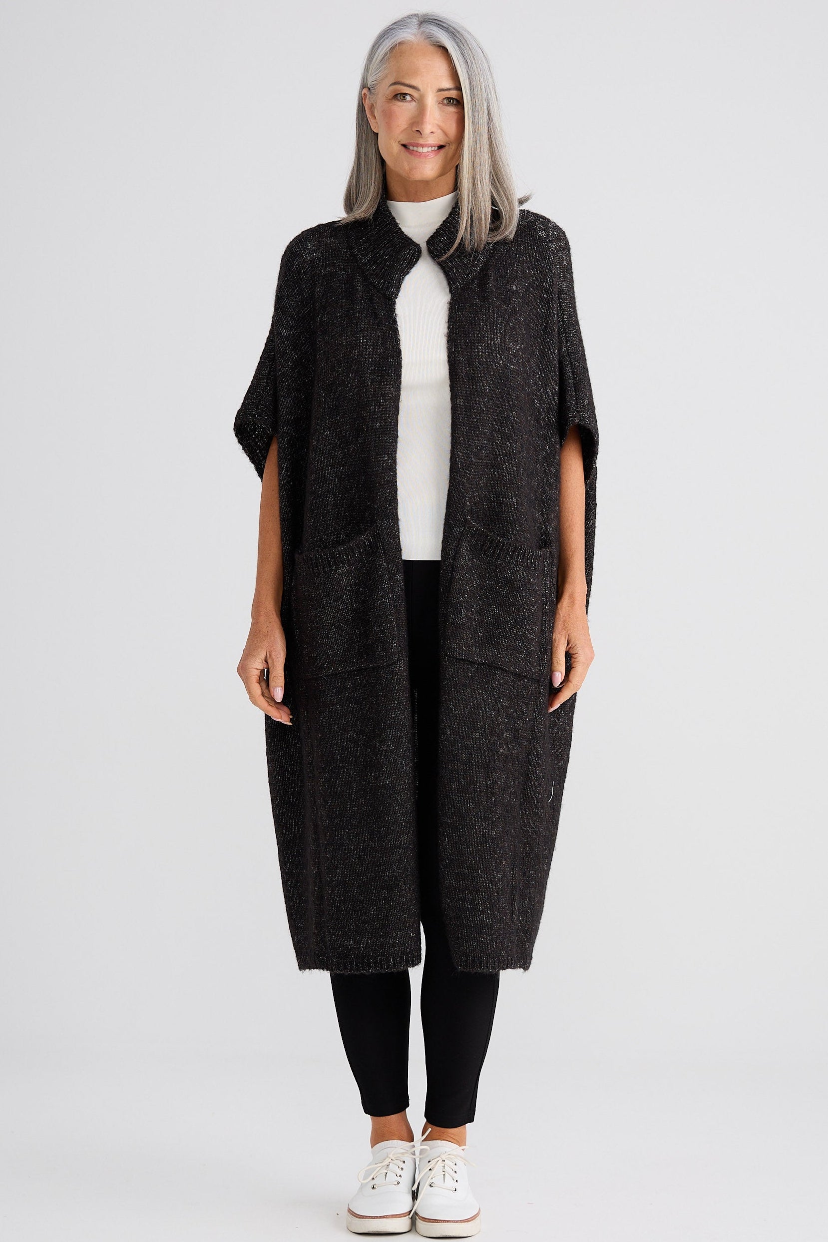 Woman wearing a dark gray long vest over a white shirt on a white background