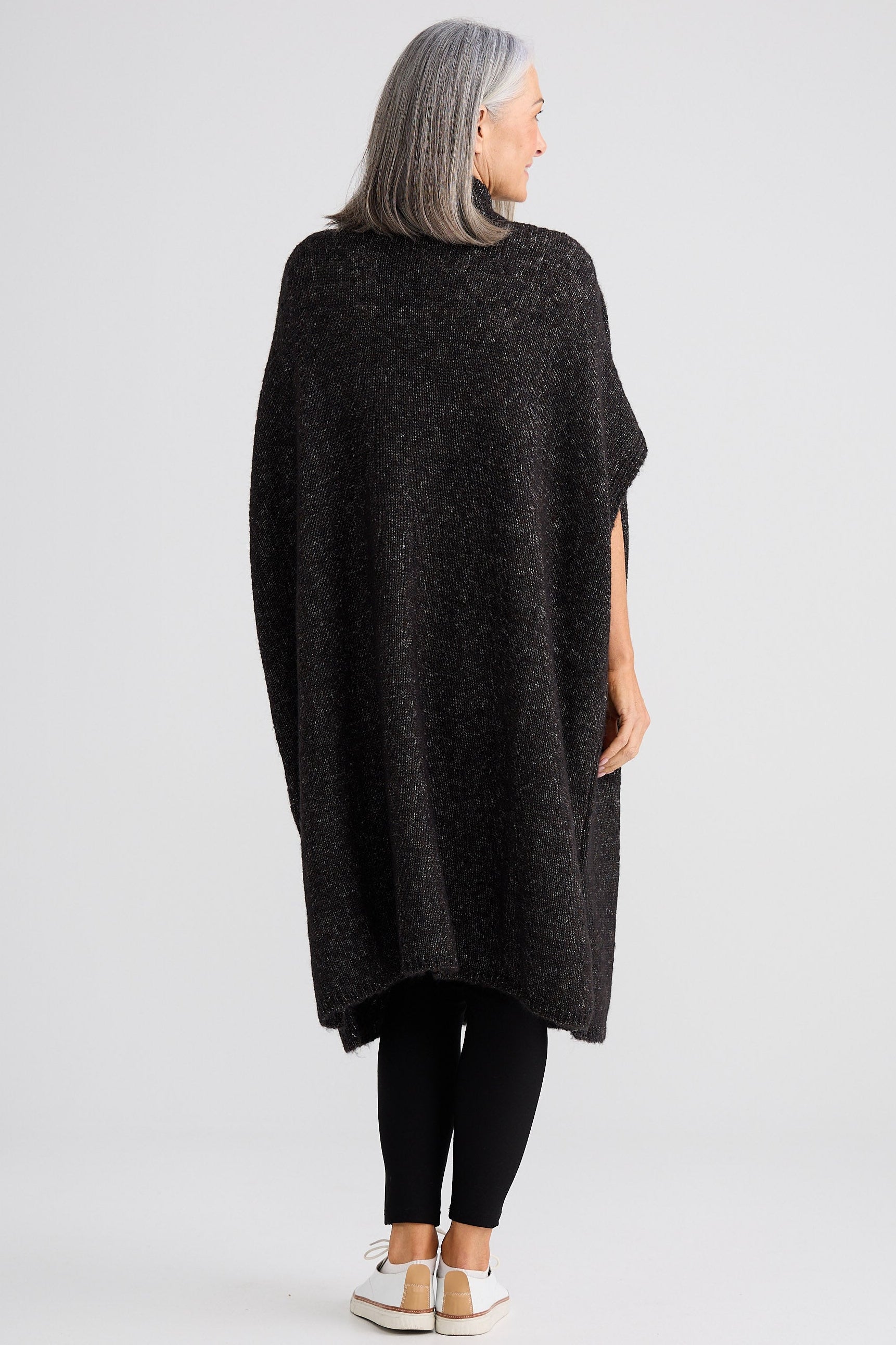 Person wearing a dark gray poncho on a light gray background