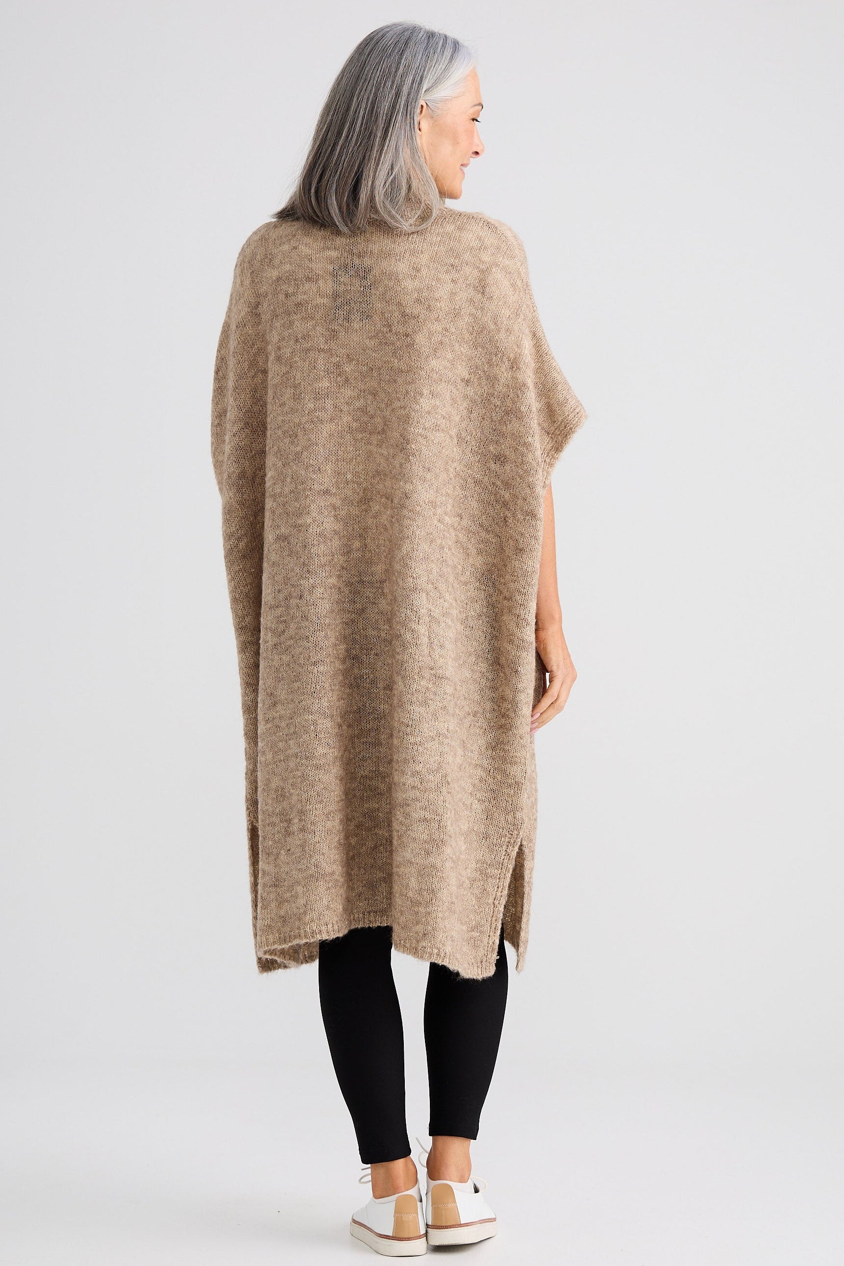Person wearing a beige poncho on a white background