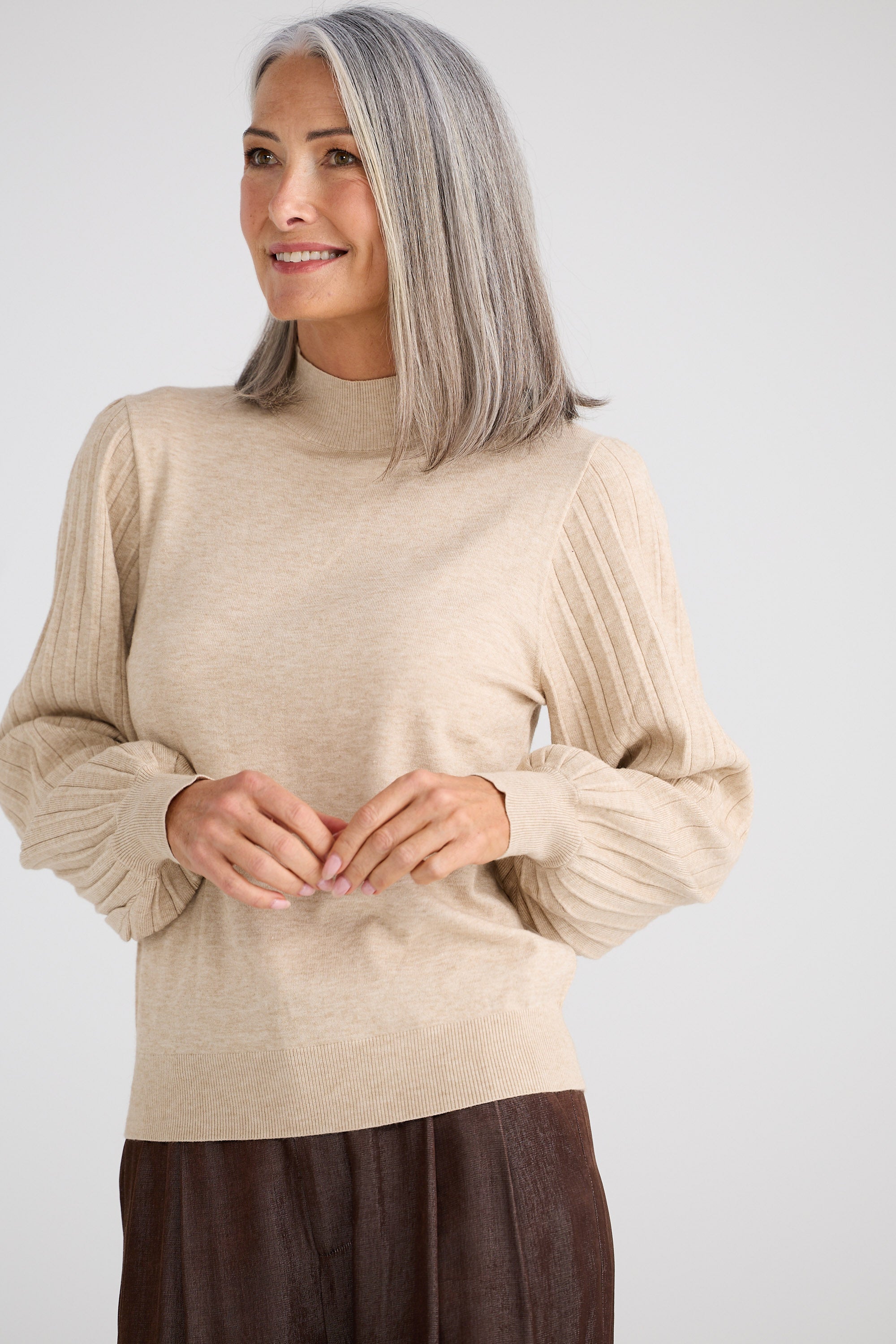 Woman wearing a beige sweater against a white background