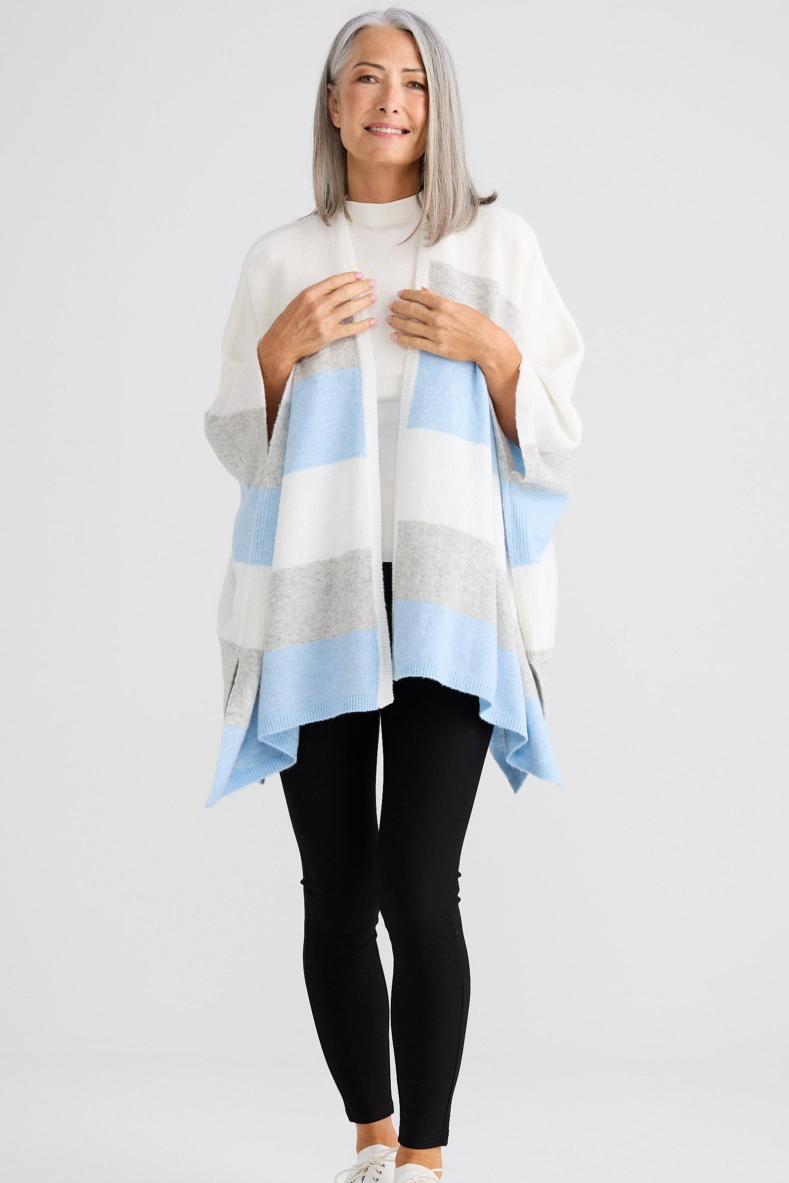 Woman wearing a light blue and gray striped poncho on a white background