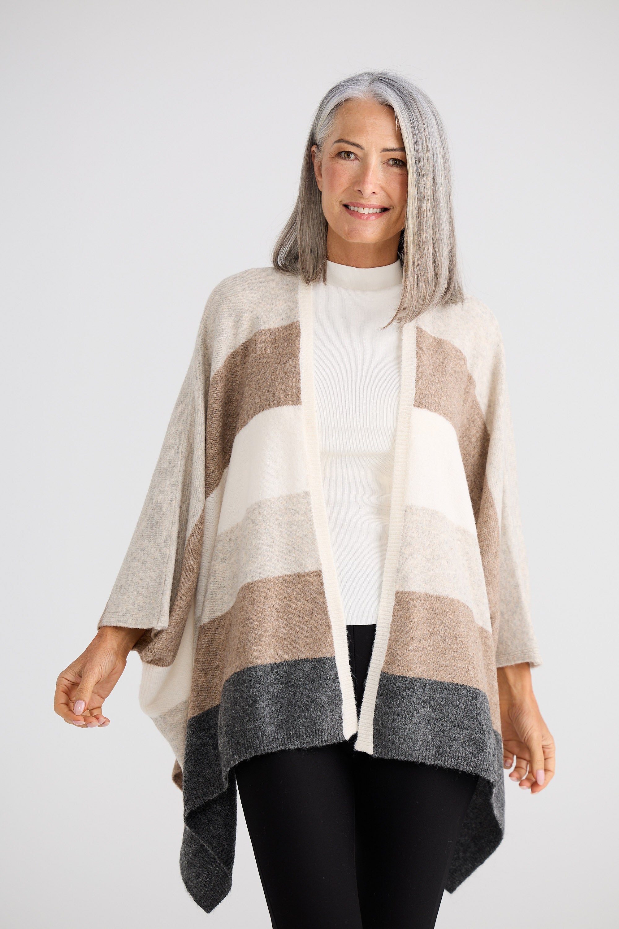 Woman wearing a striped poncho against a white background