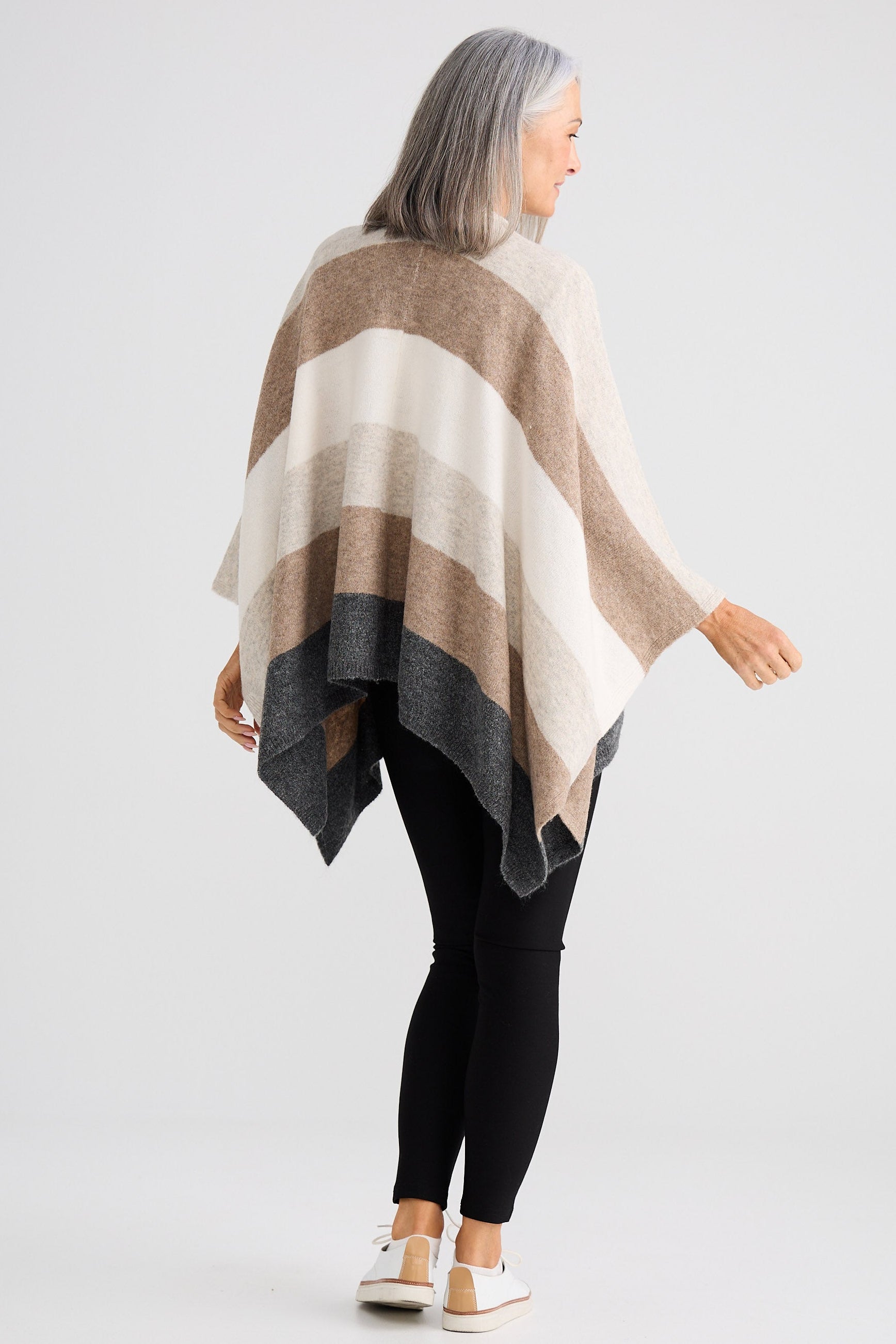 Woman wearing a striped poncho on a white background