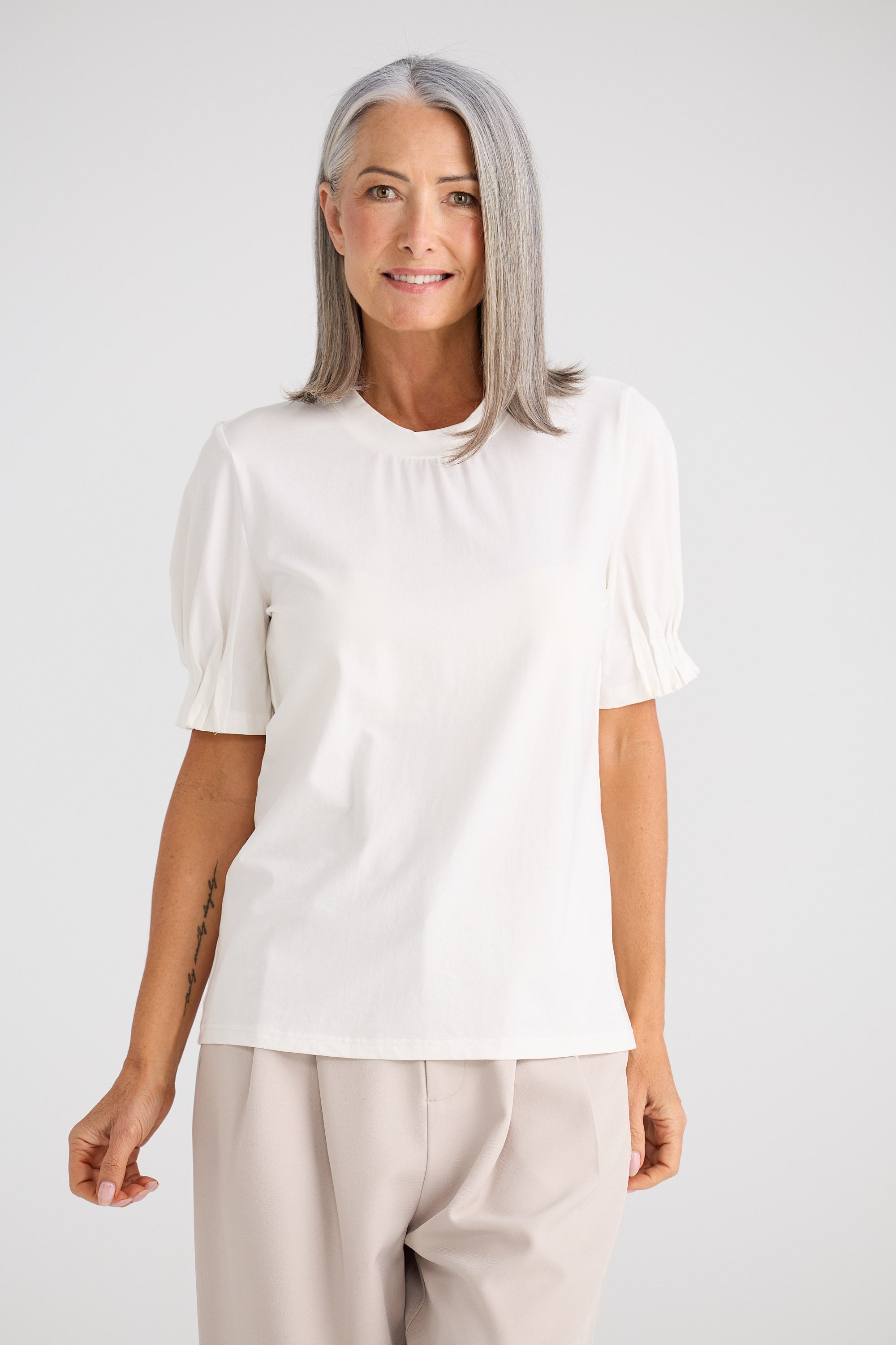 Woman wearing a white blouse with puff sleeves against a plain background