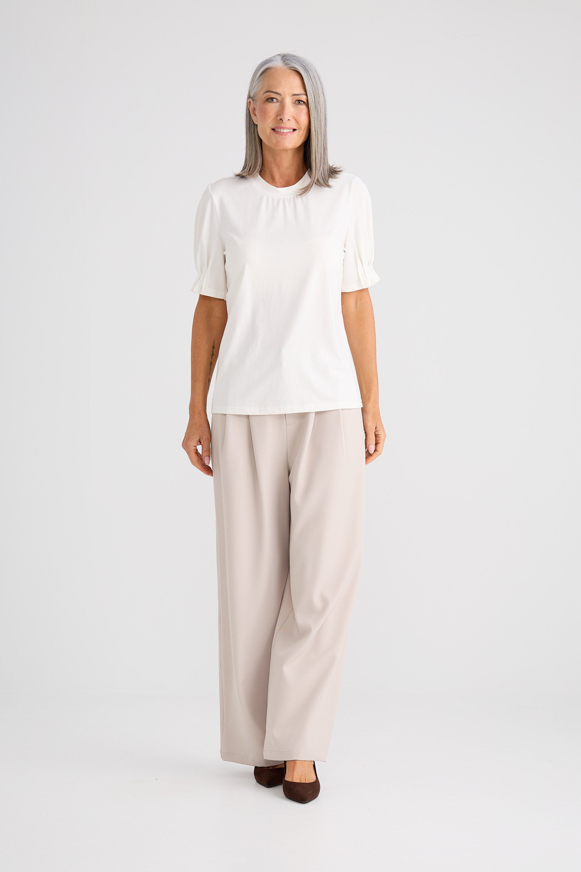 Woman wearing a white blouse and beige pants on a white background