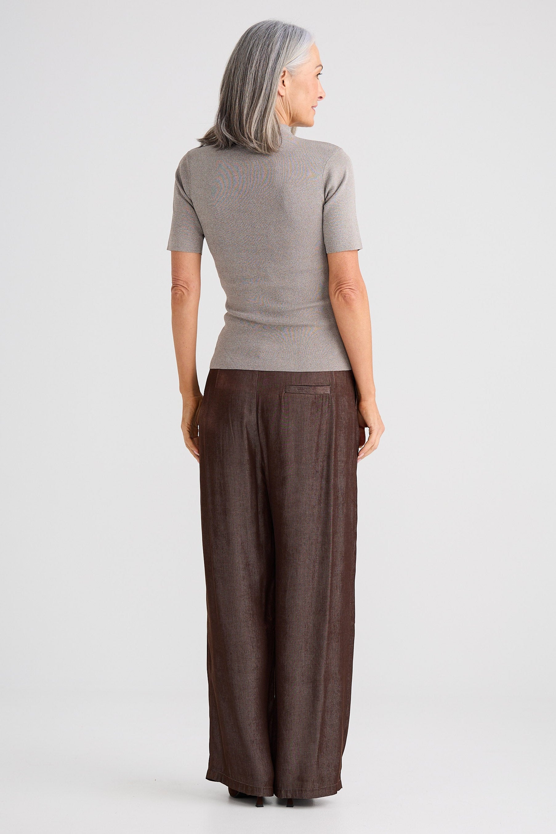 Woman wearing a gray top and brown wide-leg pants on a white background