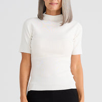 Woman wearing a white short-sleeve top and black pants on a light gray background