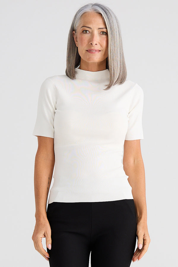 Woman wearing a white short-sleeve top and black pants on a light gray background