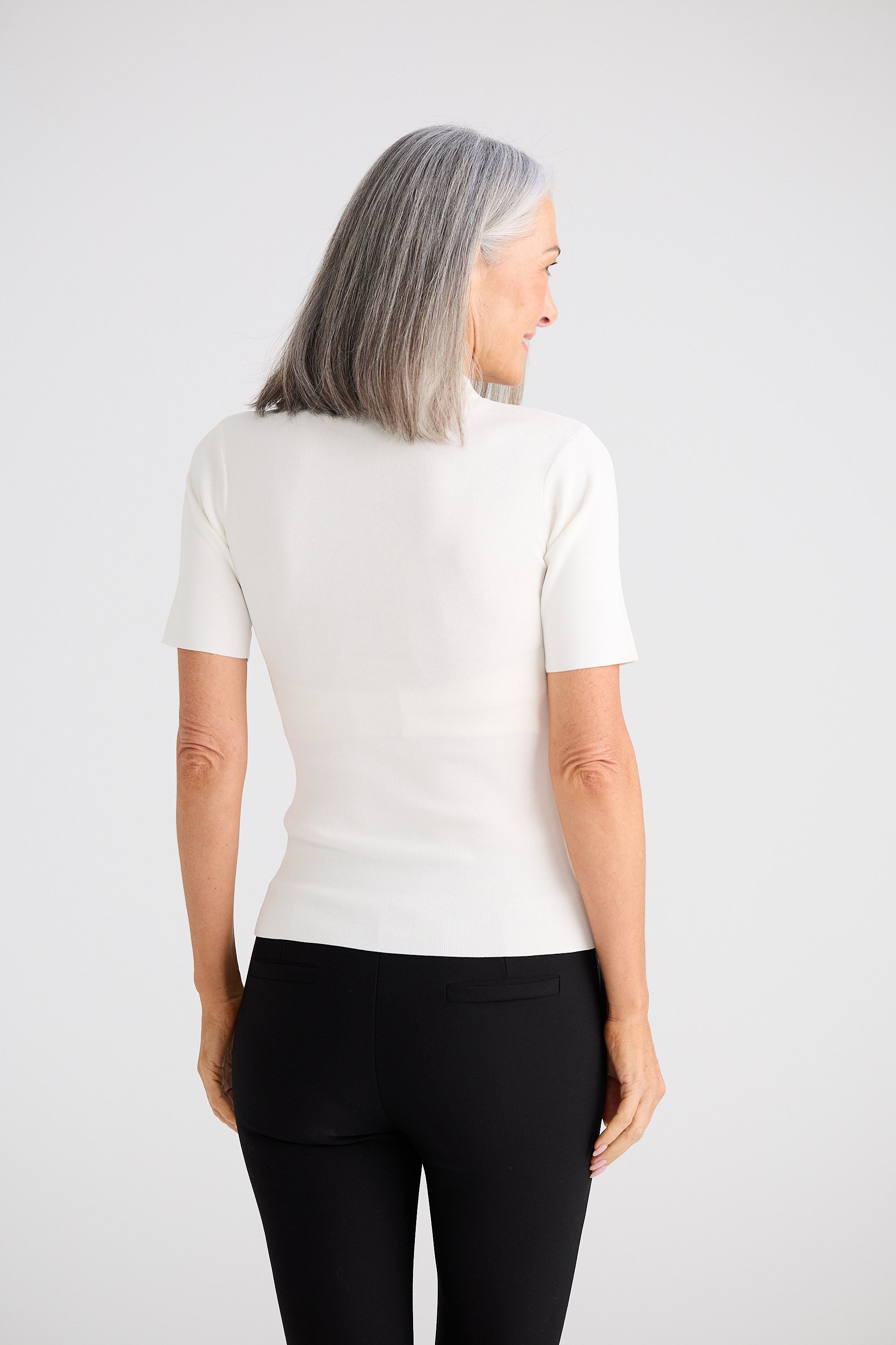 Person wearing a white short-sleeve shirt and black pants on a plain background