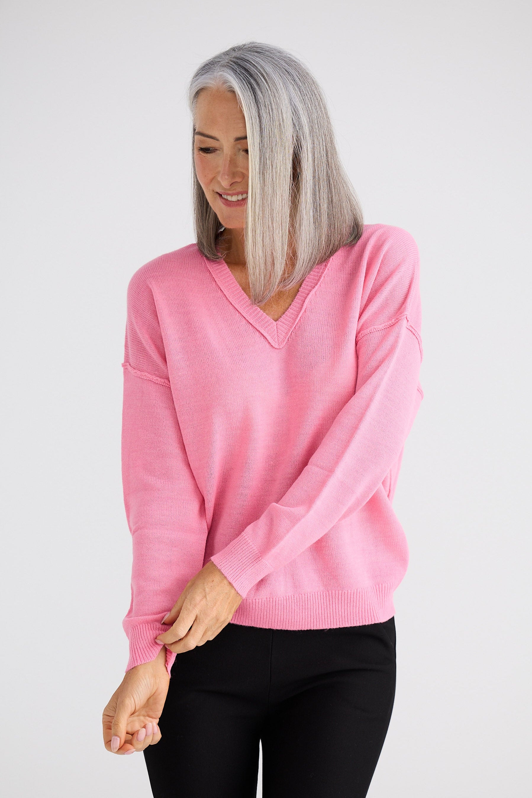 Woman wearing a pink sweater and black pants on a white background