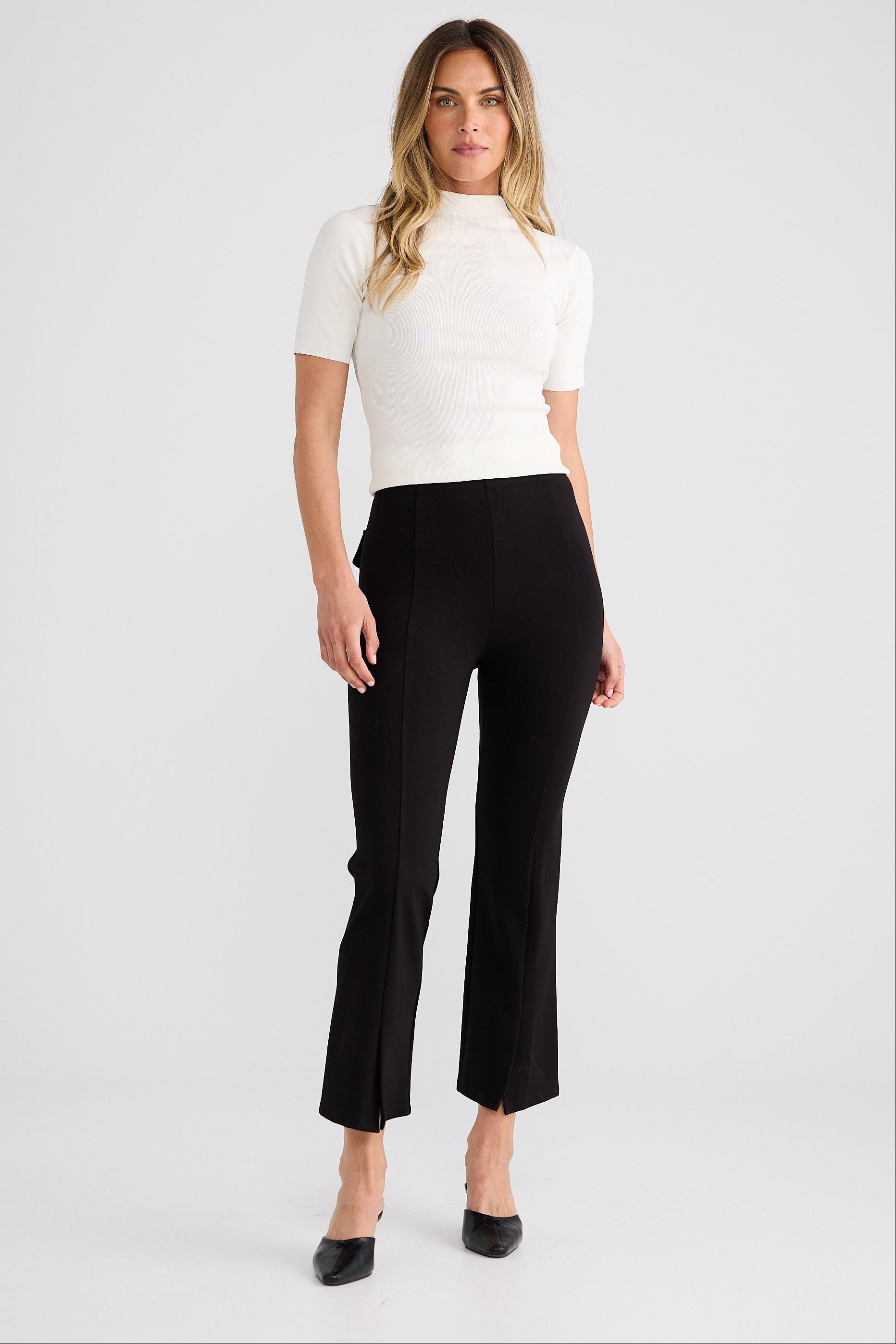 Woman wearing a white top and black pants on a white background