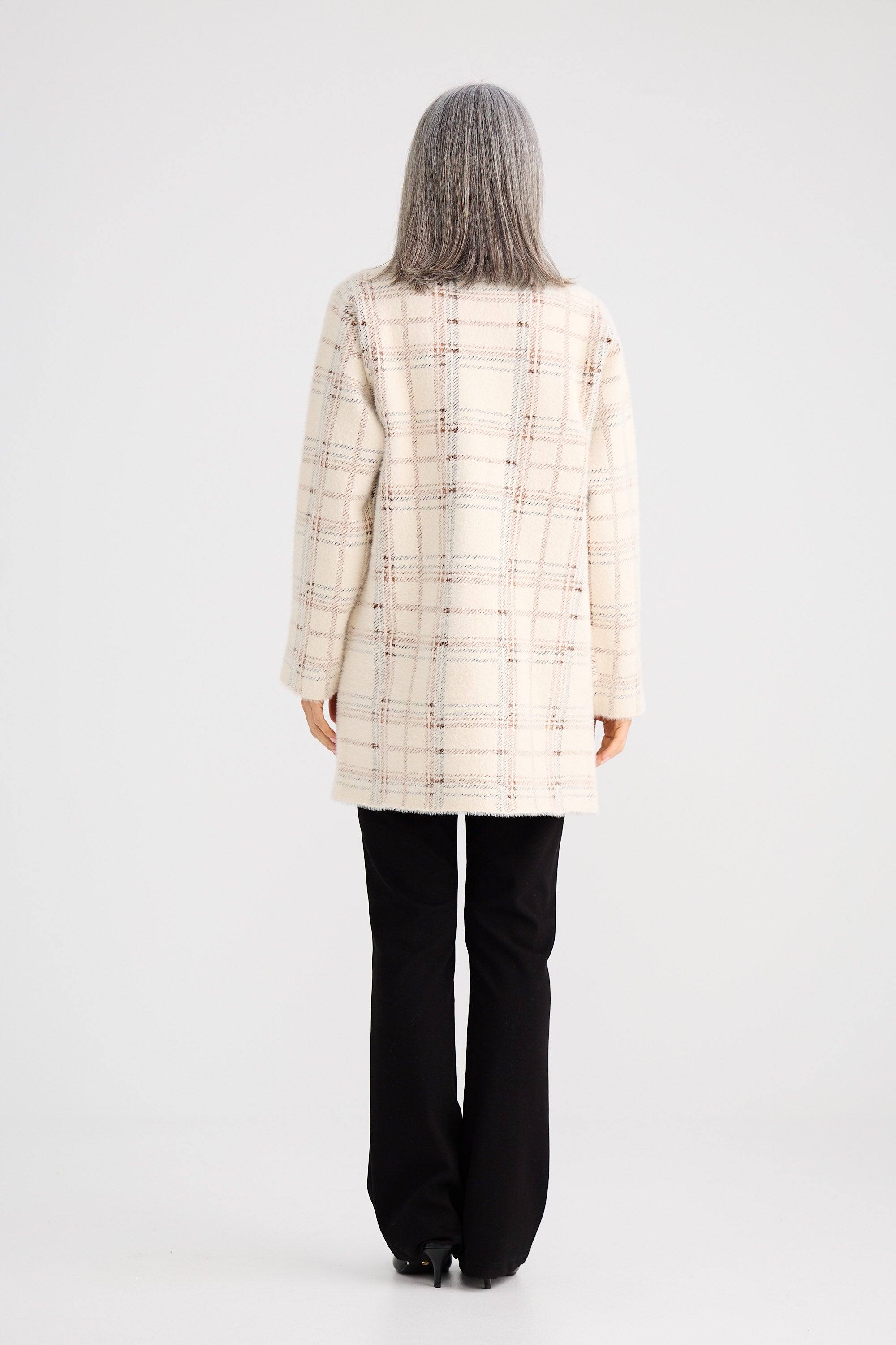 Person wearing a checkered coat and black pants on a white background