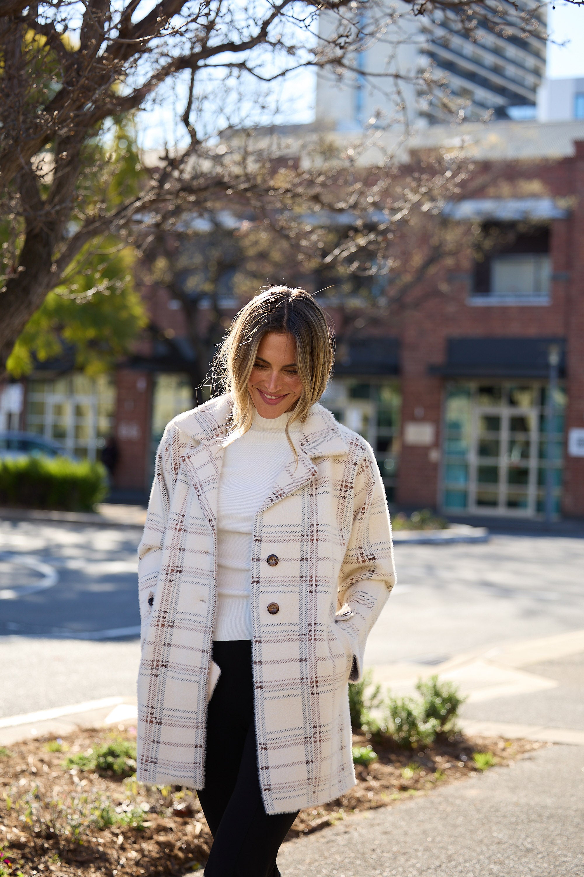 Woman wearing a plaid coat in an urban setting