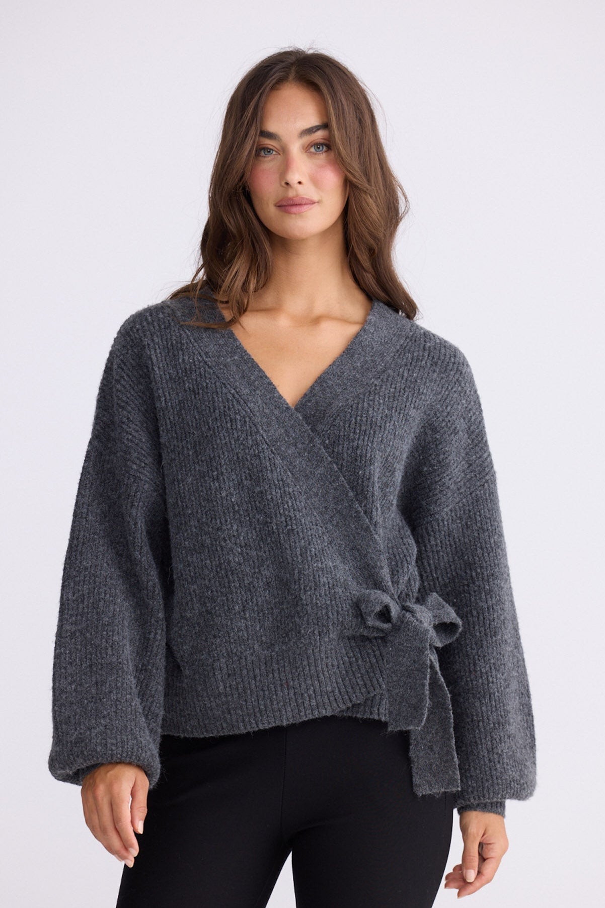 Model wearing Monteith Wrap Knit in grey with V-neck and wrap front, front view on white background