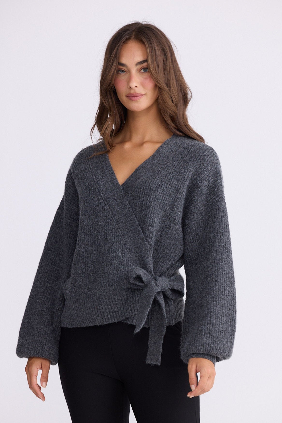 Model wearing Monteith Wrap Knit in grey with V-neck and wrap front, front view on white background