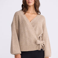 Model wearing Monteith Wrap Knit in beige with V-neck and wrap front, front view on white background