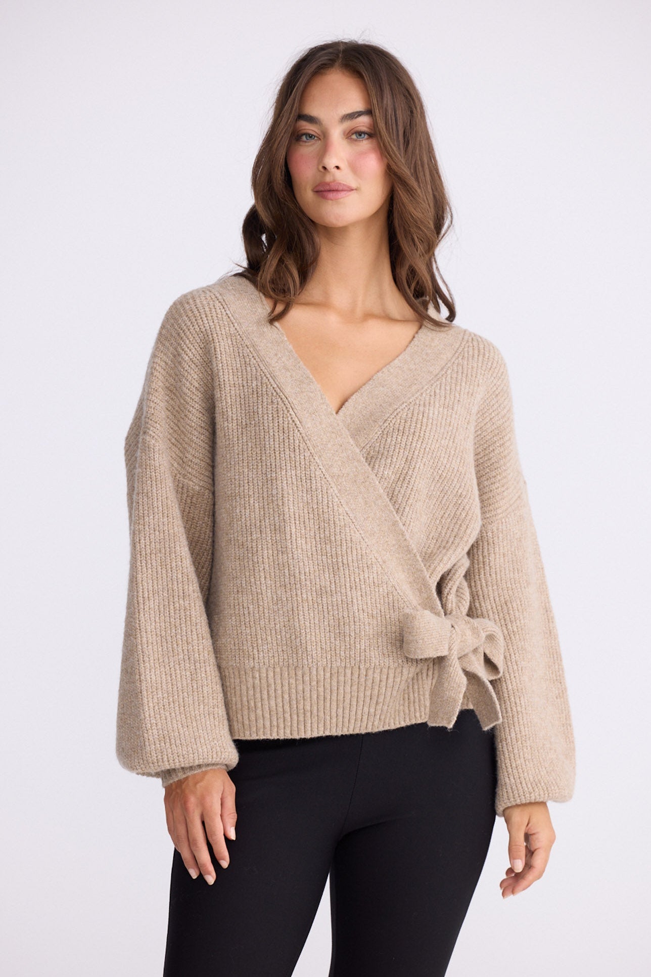 Model wearing Monteith Wrap Knit in beige with V-neck and wrap front, front view on white background