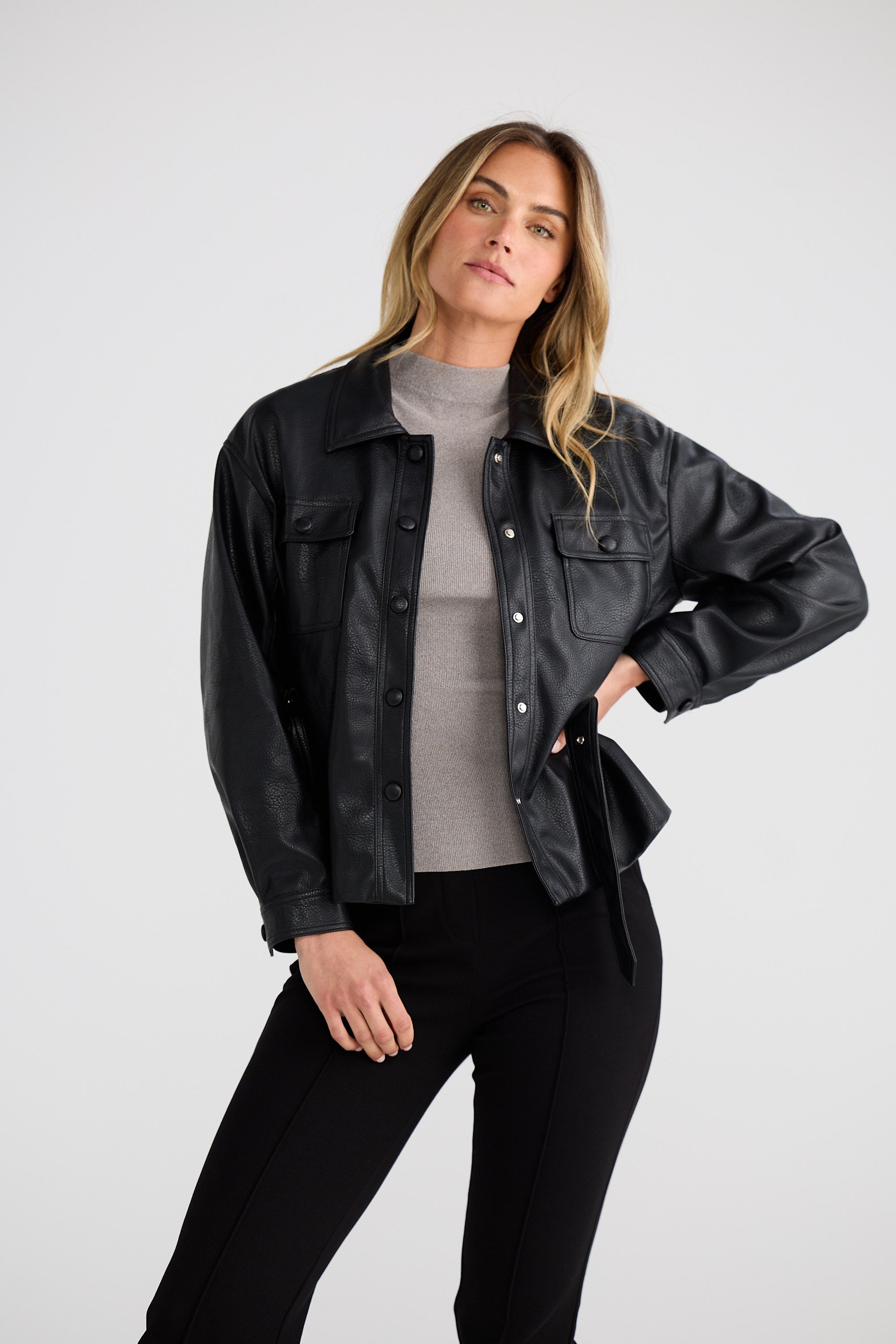 Woman wearing a black jacket over a gray shirt on a white background