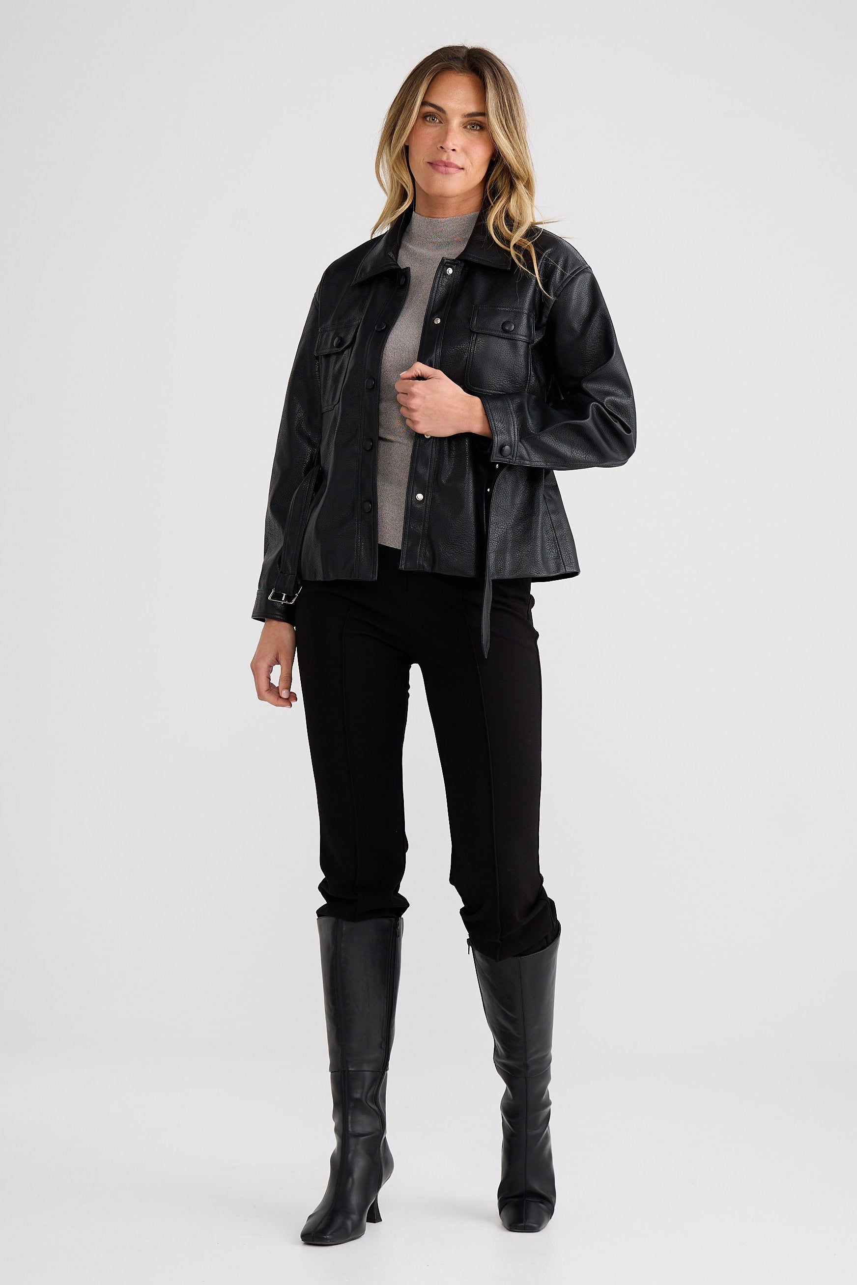 Woman wearing a black jacket, black pants, and black boots on a white background