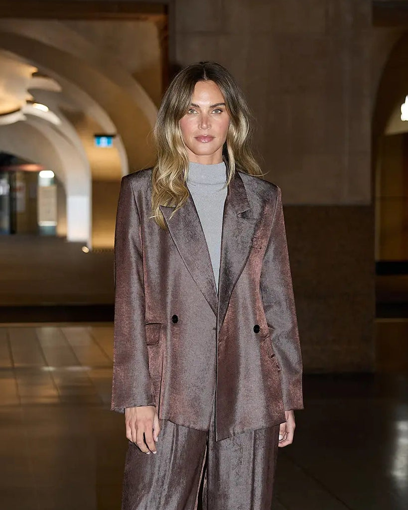 Woman in a brown suit standing in an elegant interior setting