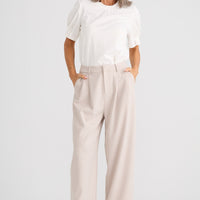 Woman wearing a white blouse and beige pants on a white background