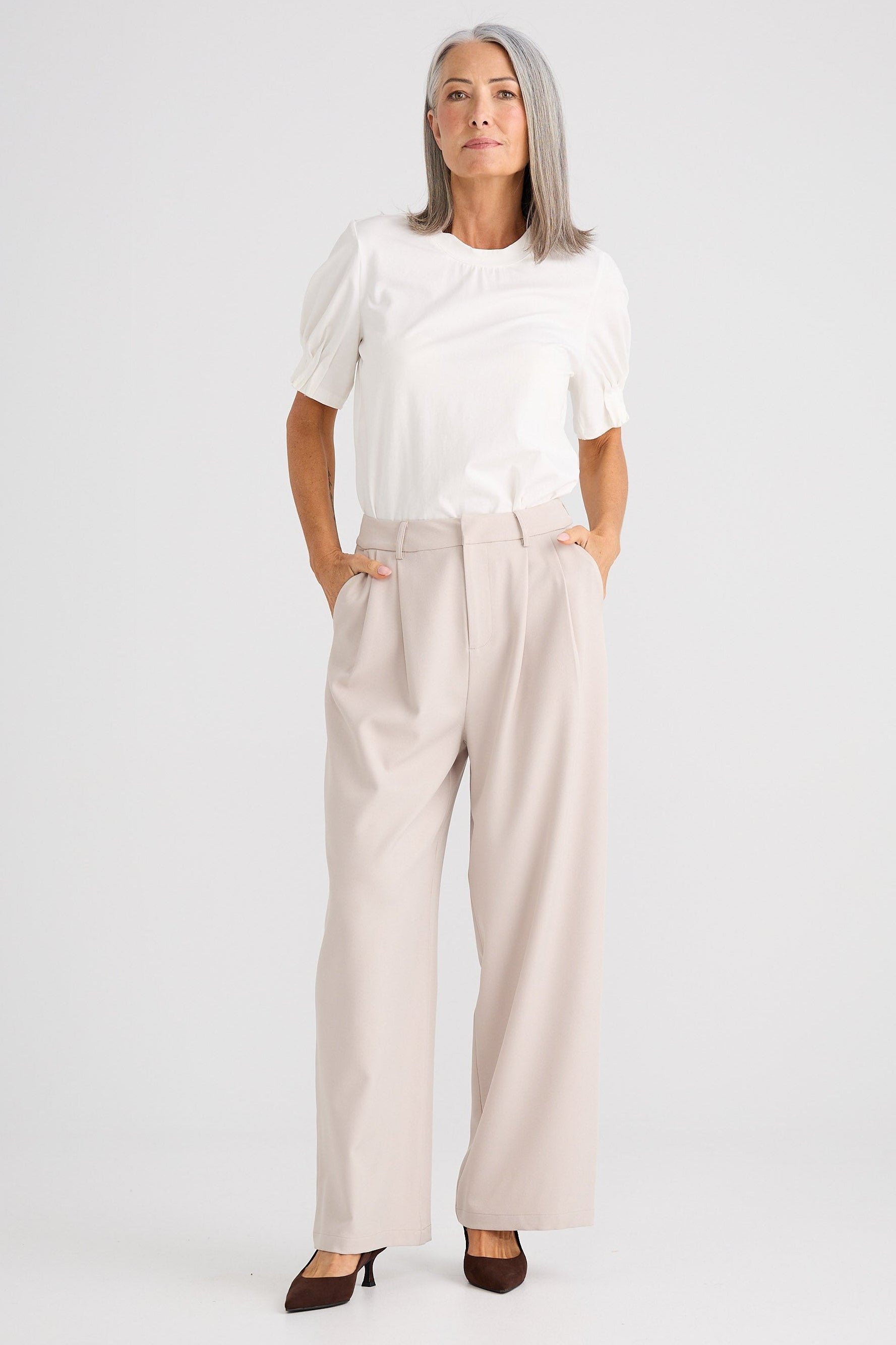 Woman wearing a white blouse and beige pants on a white background