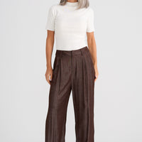 Woman wearing a white top and brown wide-leg pants on a white background