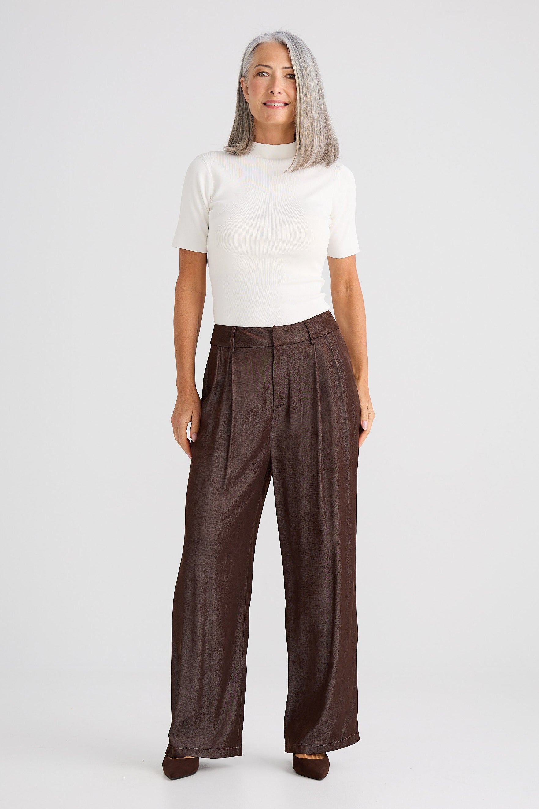 Woman wearing a white top and brown wide-leg pants on a white background