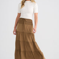 Woman wearing a white top and brown tiered skirt on a white background