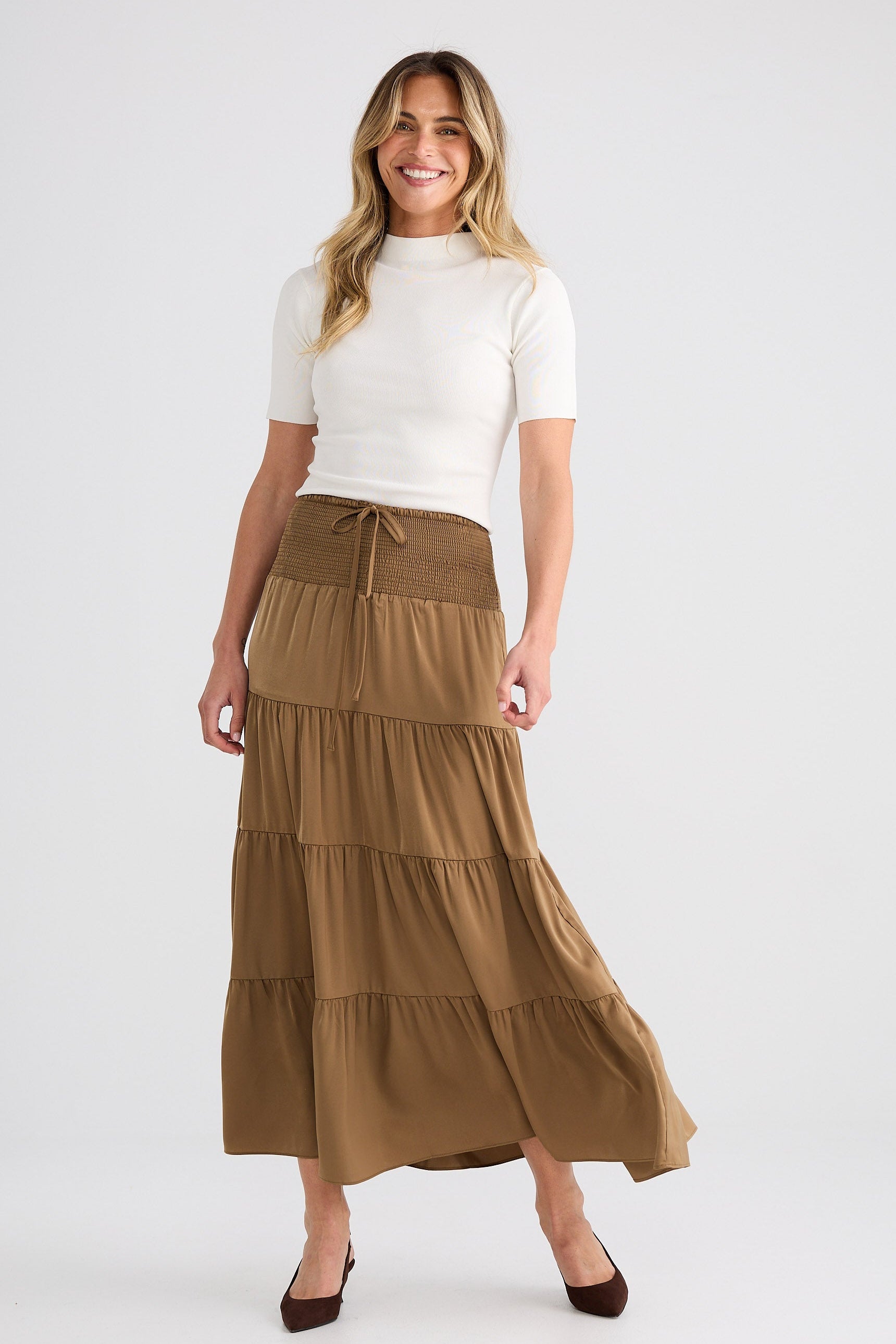 Woman wearing a white top and brown tiered skirt on a white background