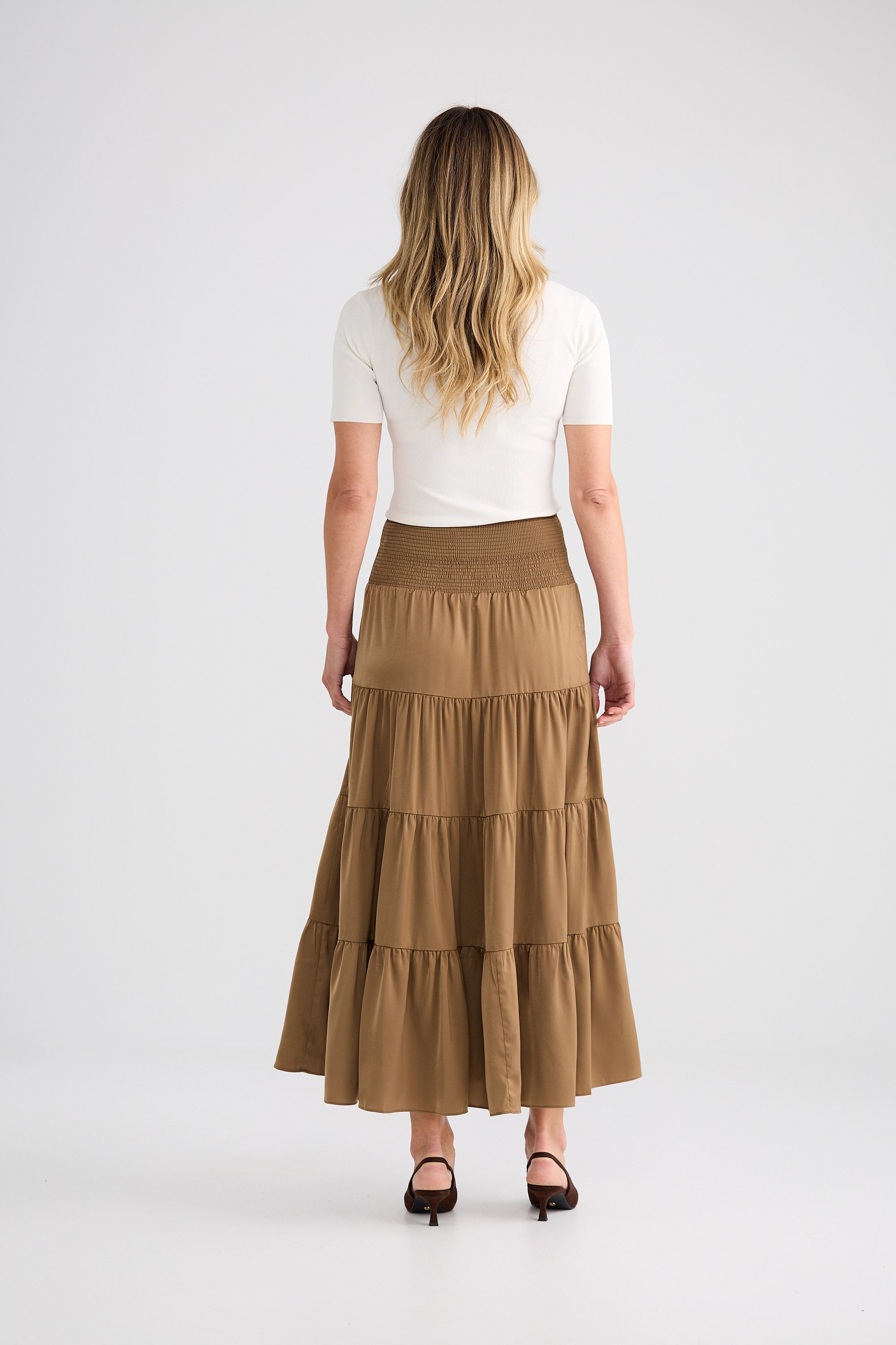 Woman wearing a brown tiered skirt and white top on a white background