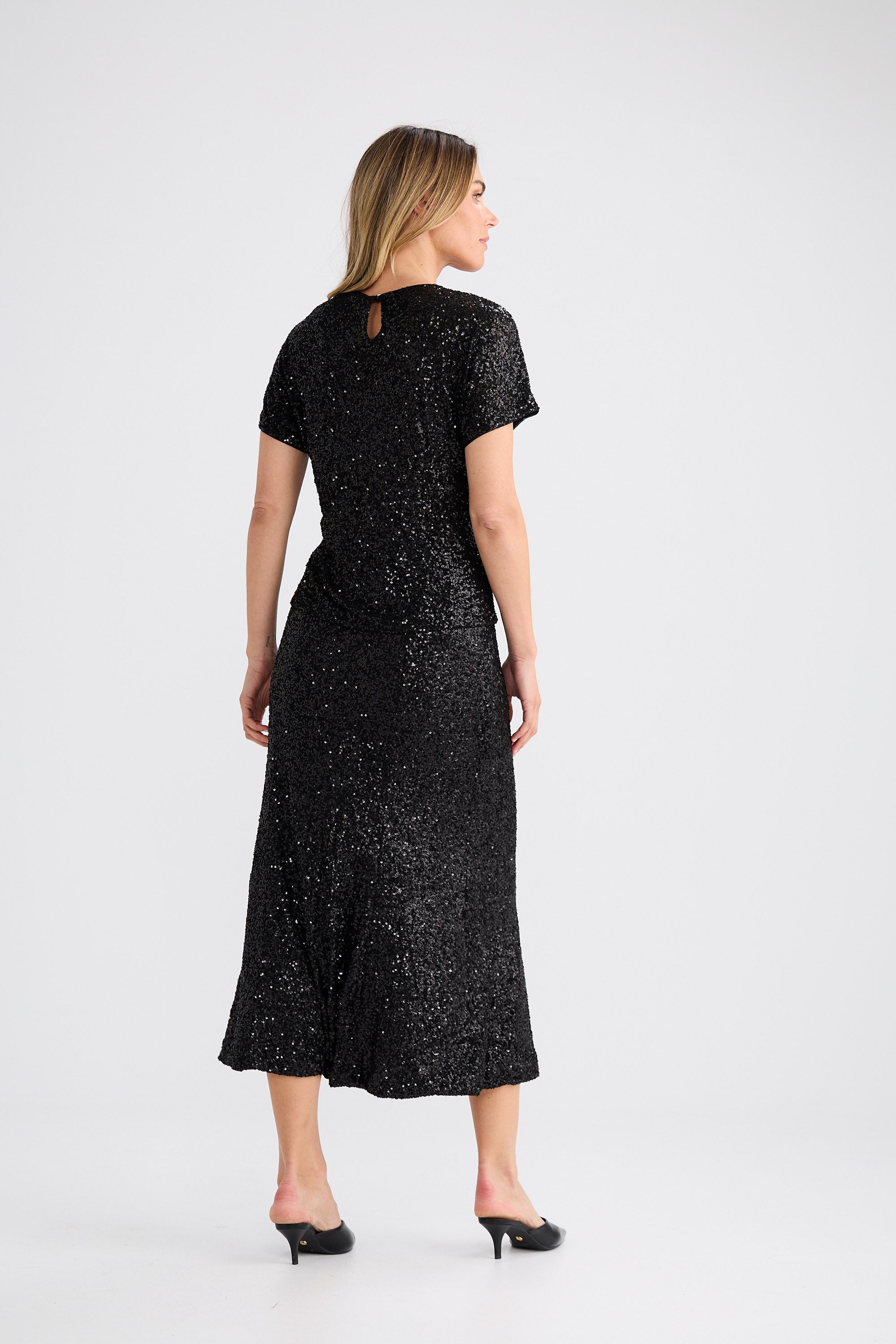 Woman wearing a black sequin dress on a white background