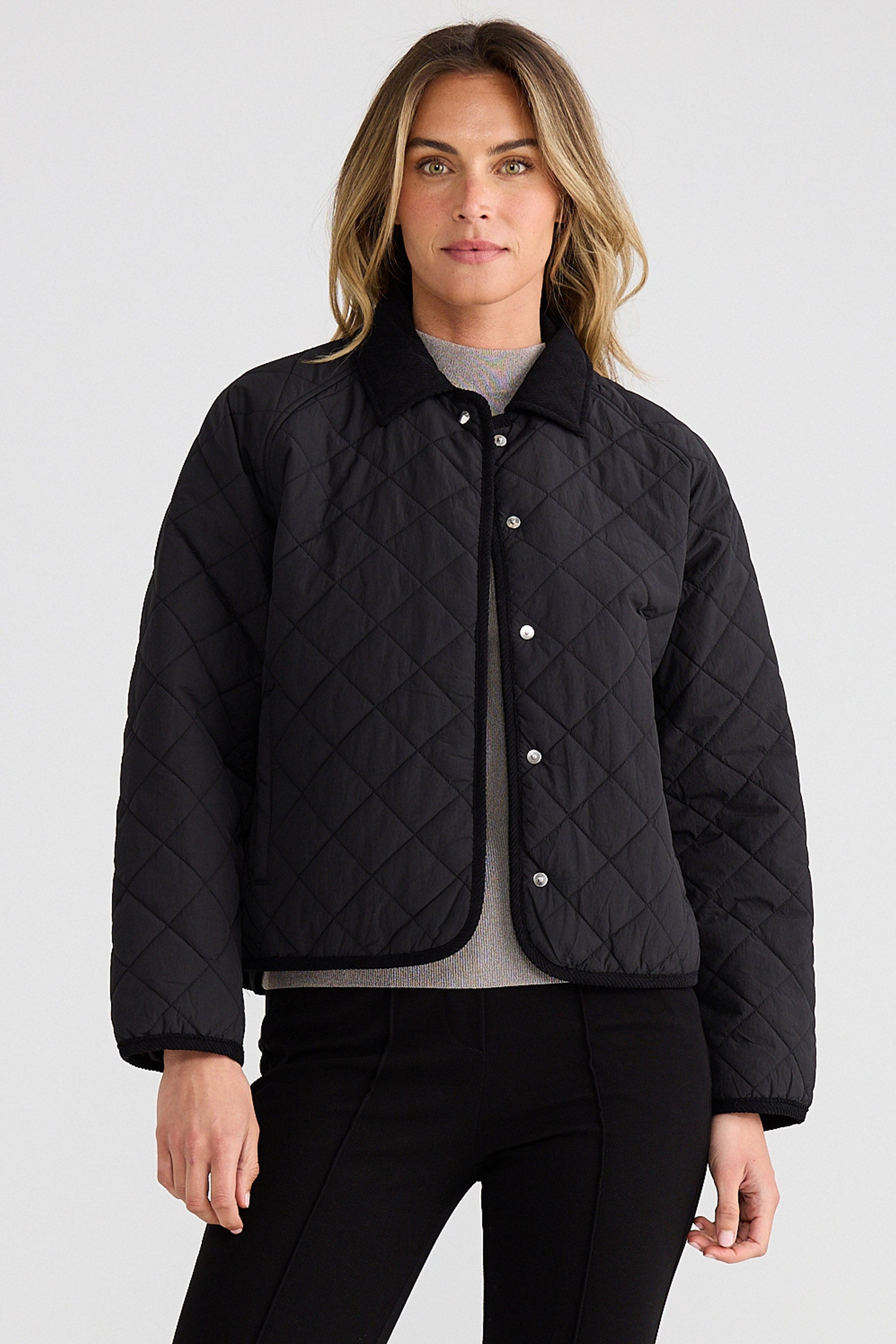 Woman wearing a black quilted jacket on a light gray background