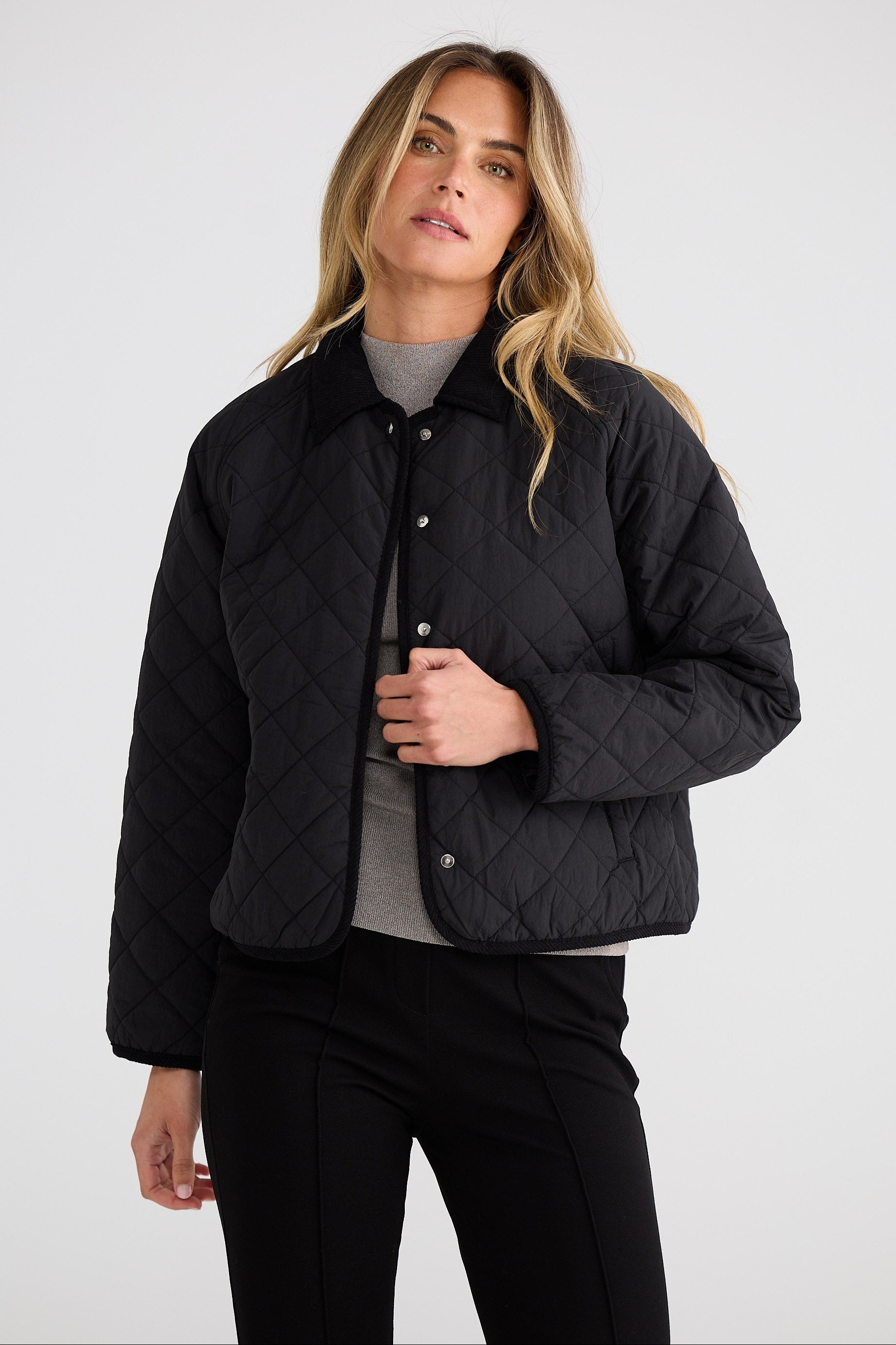 Woman wearing a black quilted jacket on a white background