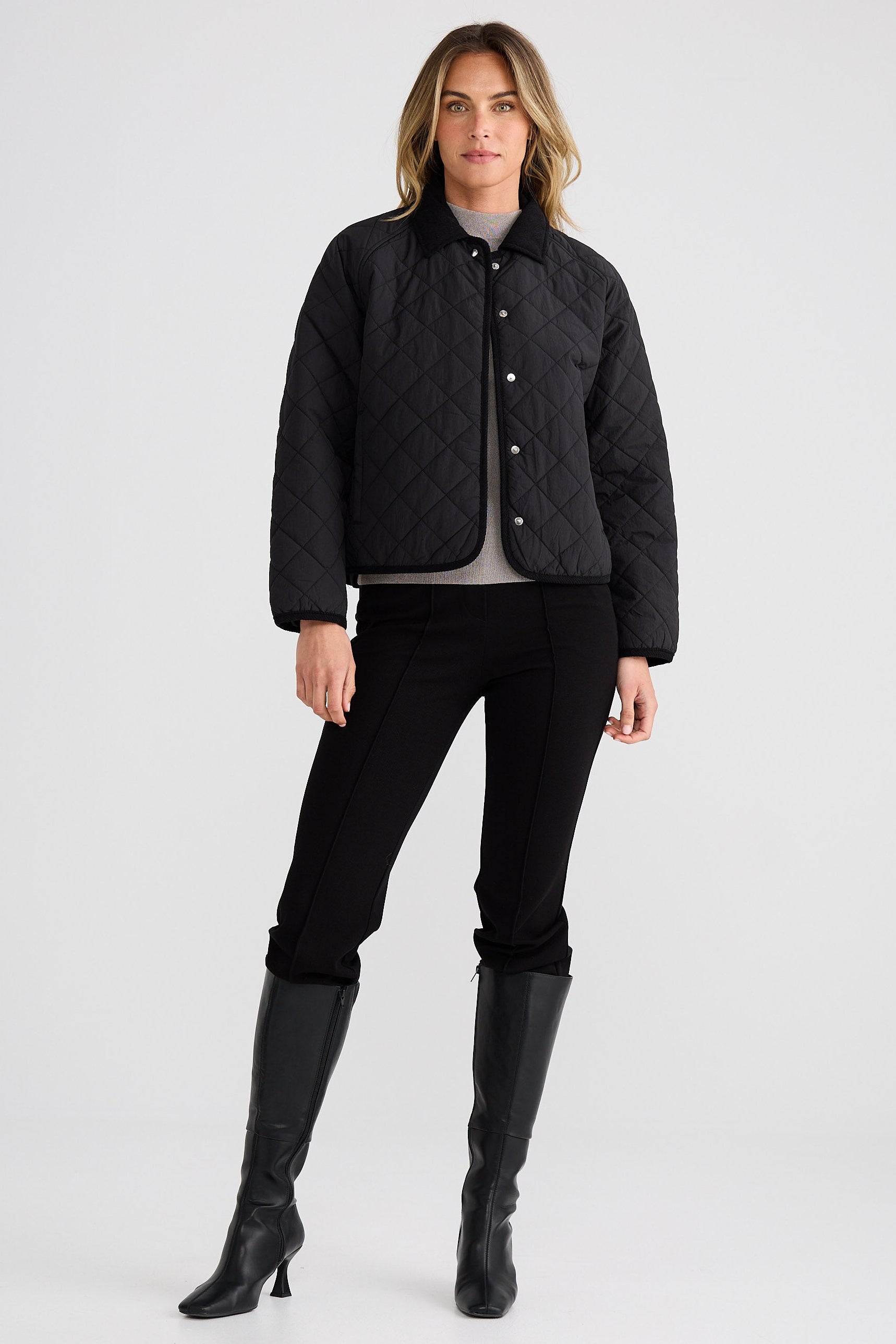 Person wearing a black quilted jacket, black pants, and black boots on a white background
