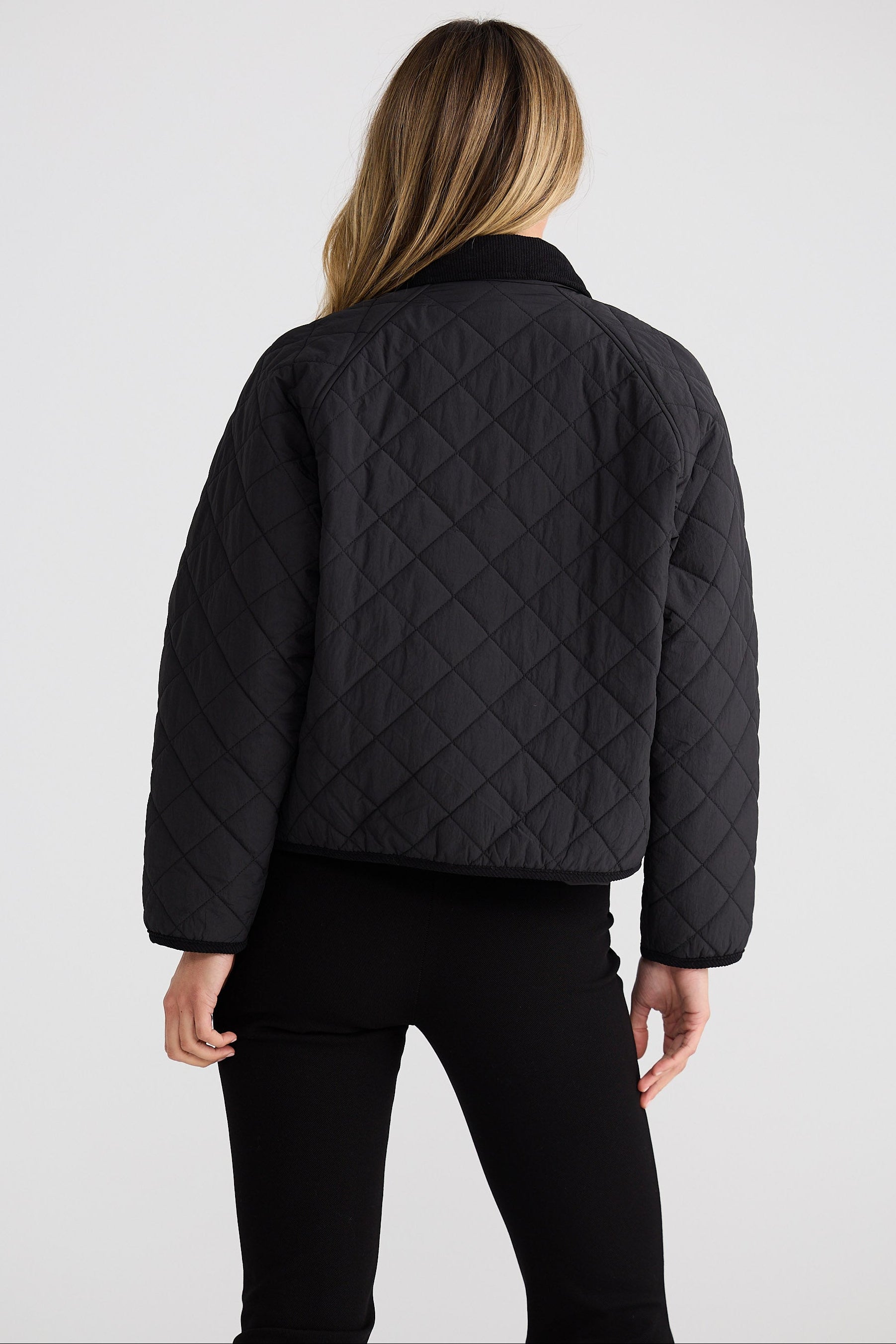 Person wearing a black quilted jacket on a light gray background