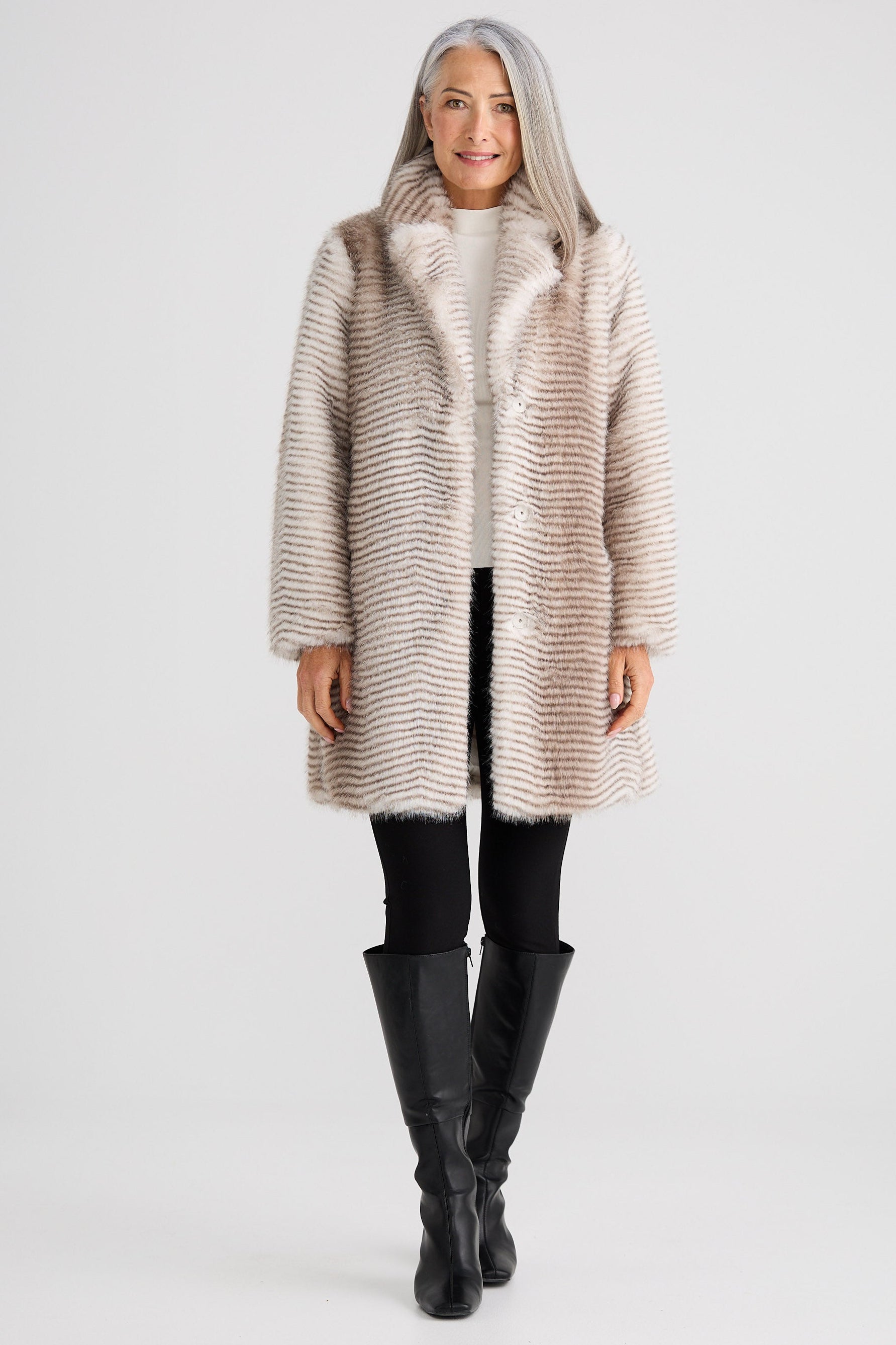 Woman wearing a long, textured coat with a hood on a white background