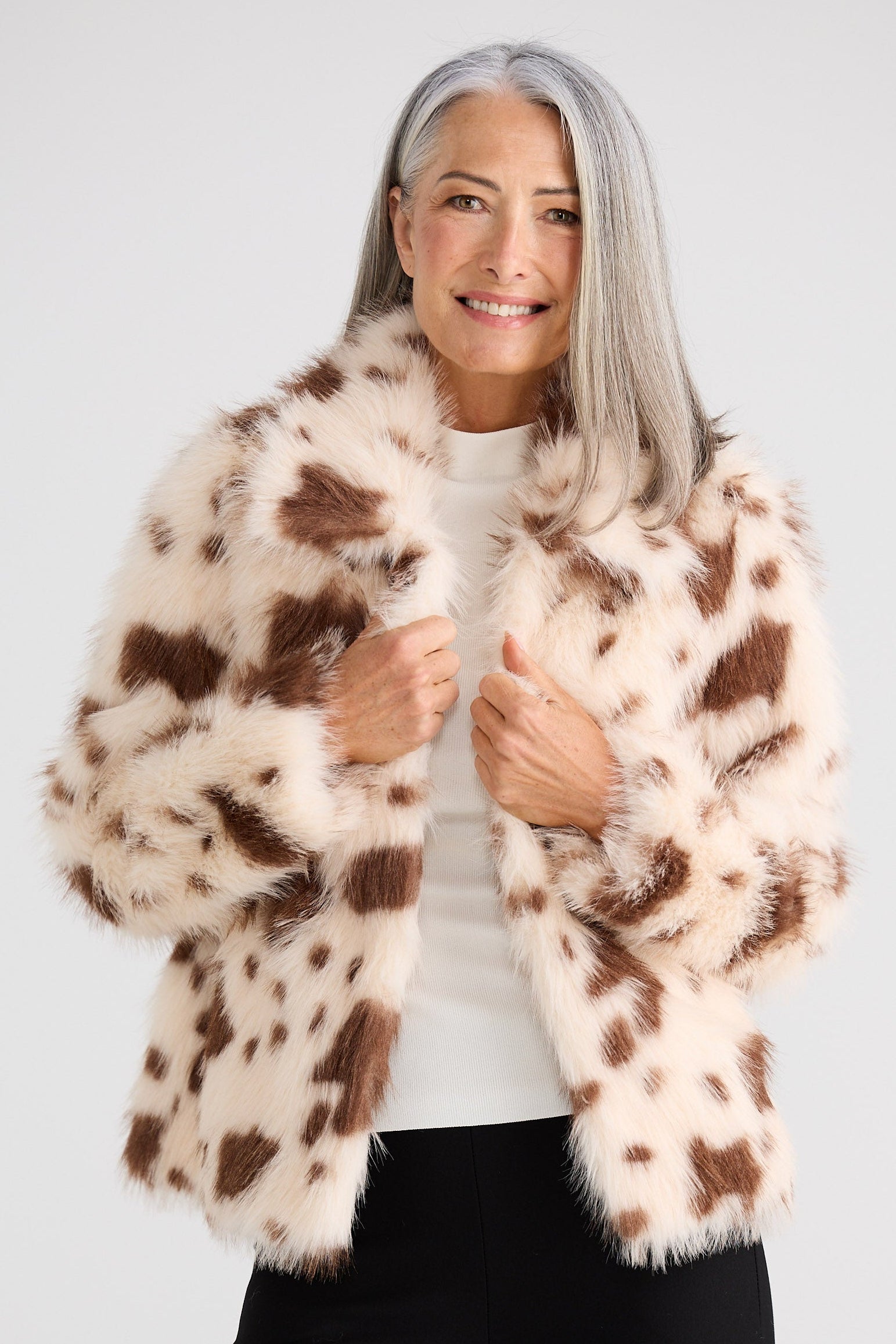 Woman wearing a brown and white patterned fur coat on a white background