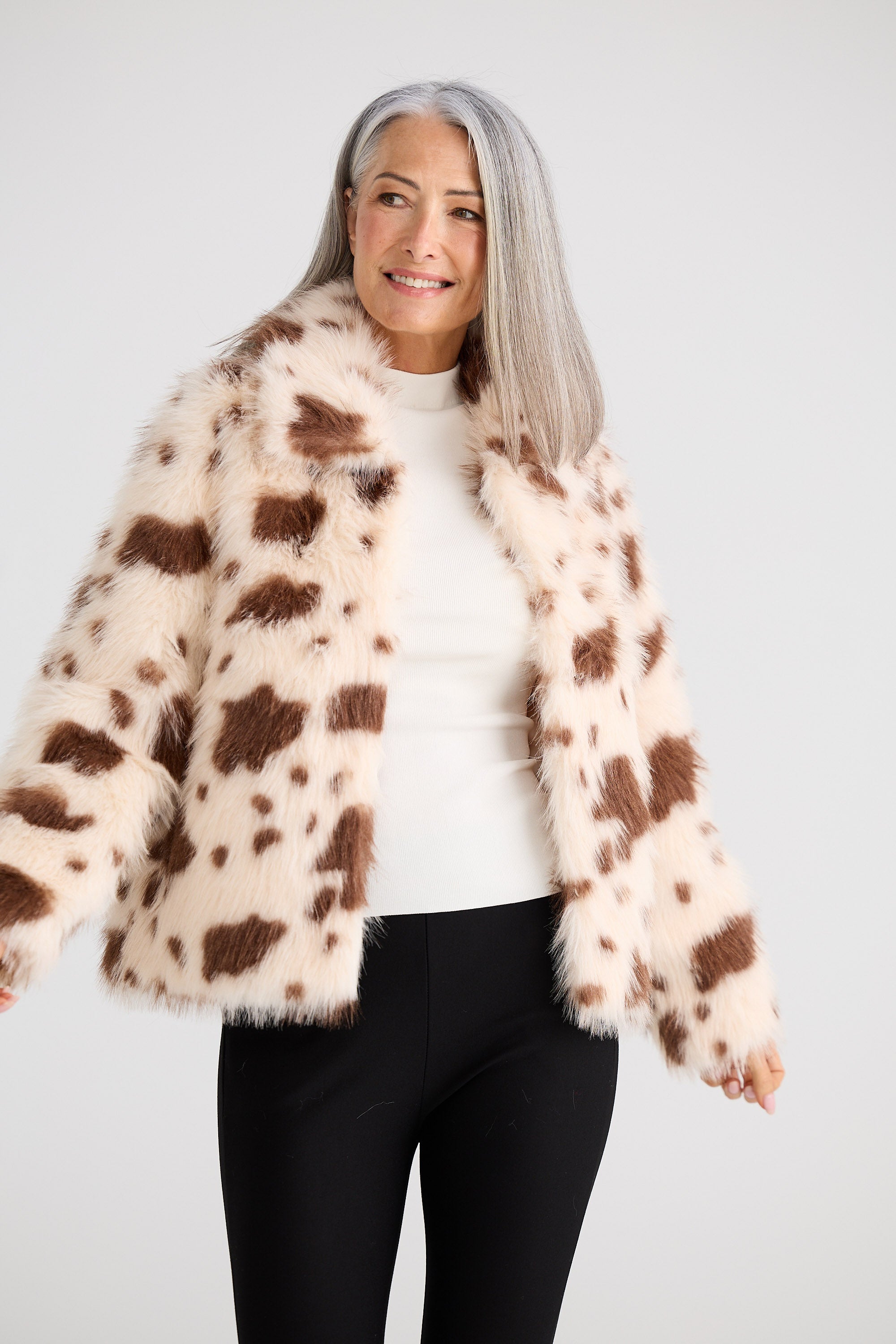 Woman wearing a cow print fur coat on a white background