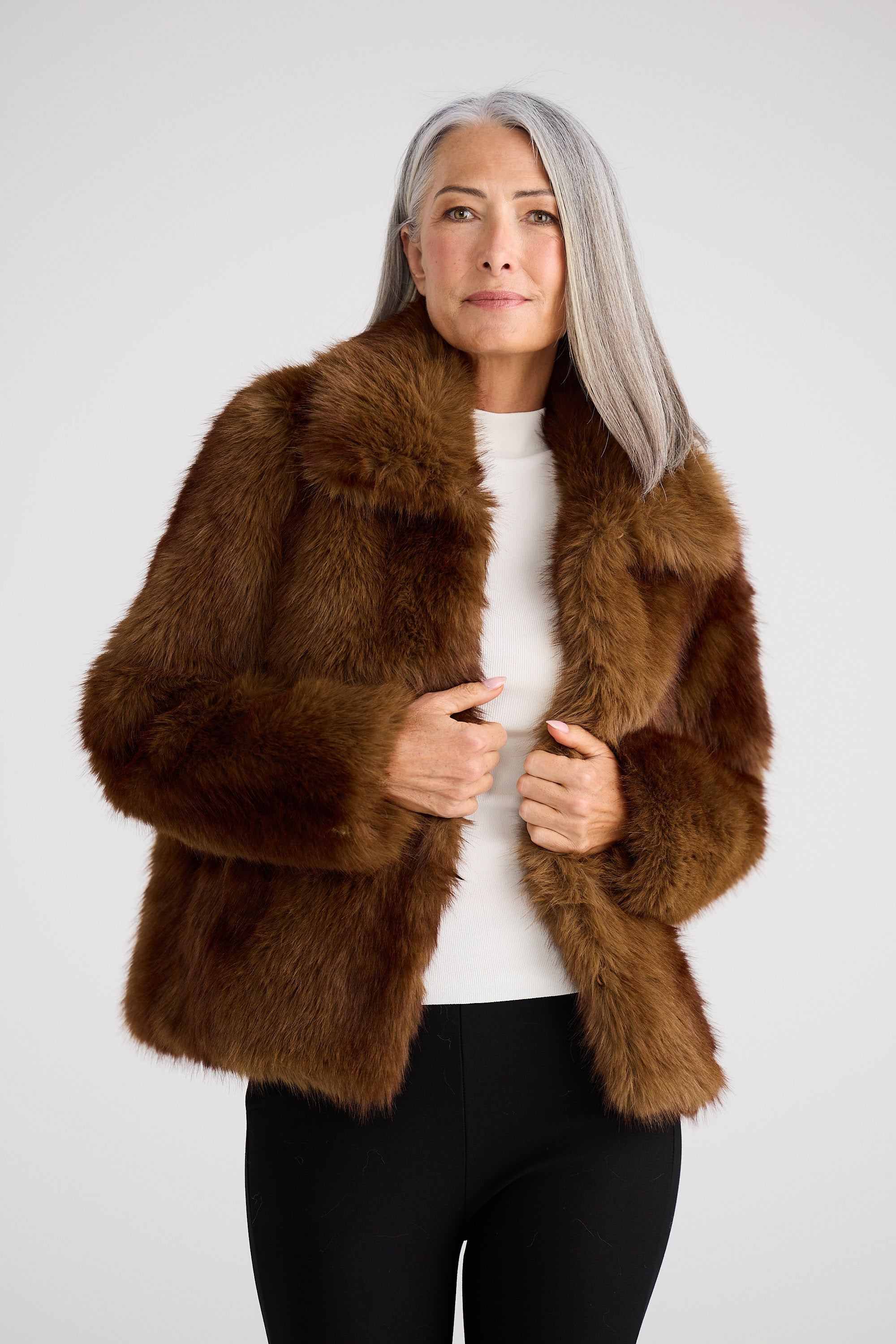 Woman wearing a brown fur coat against a white background