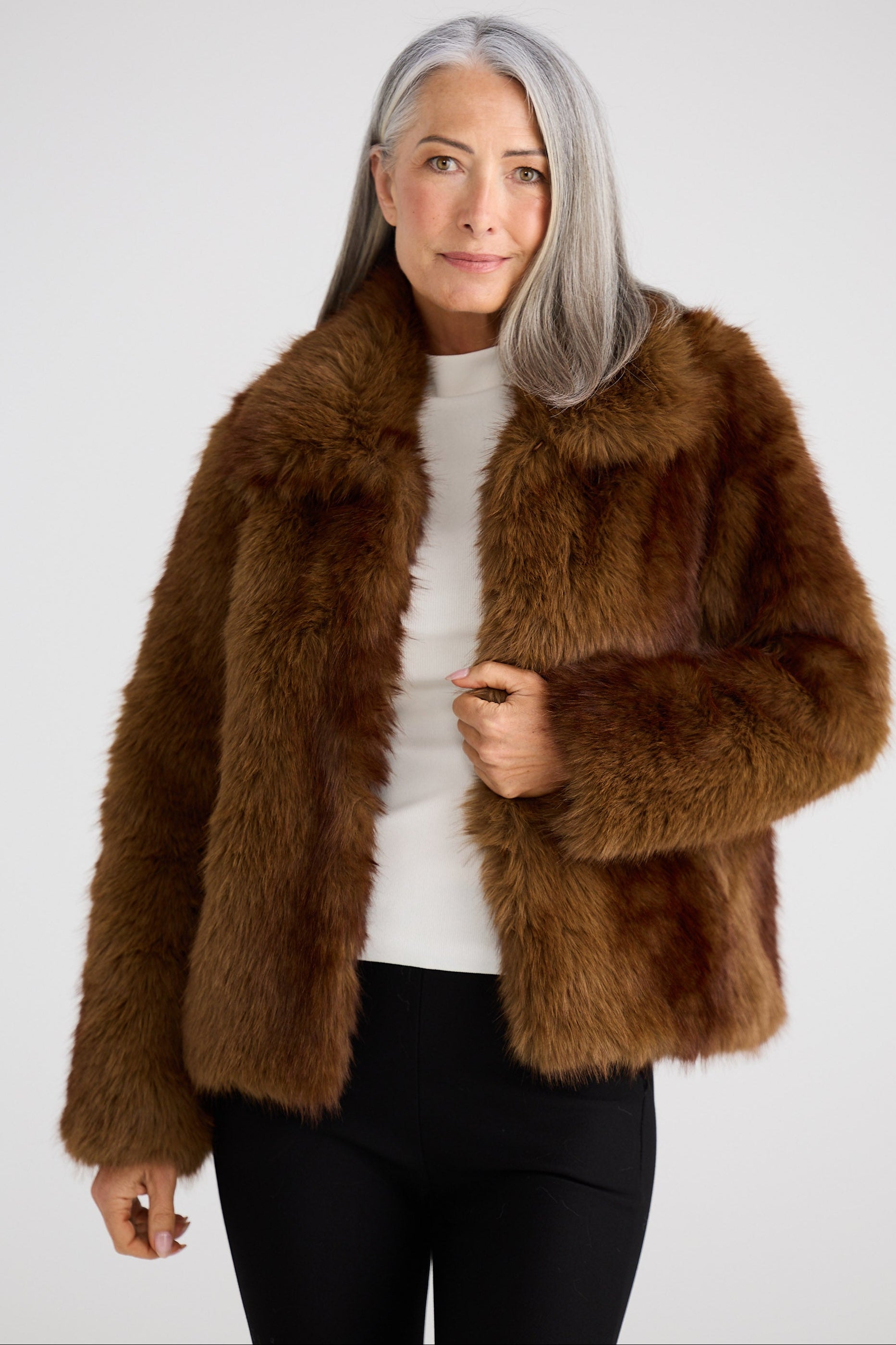 Woman wearing a brown fur coat against a white background