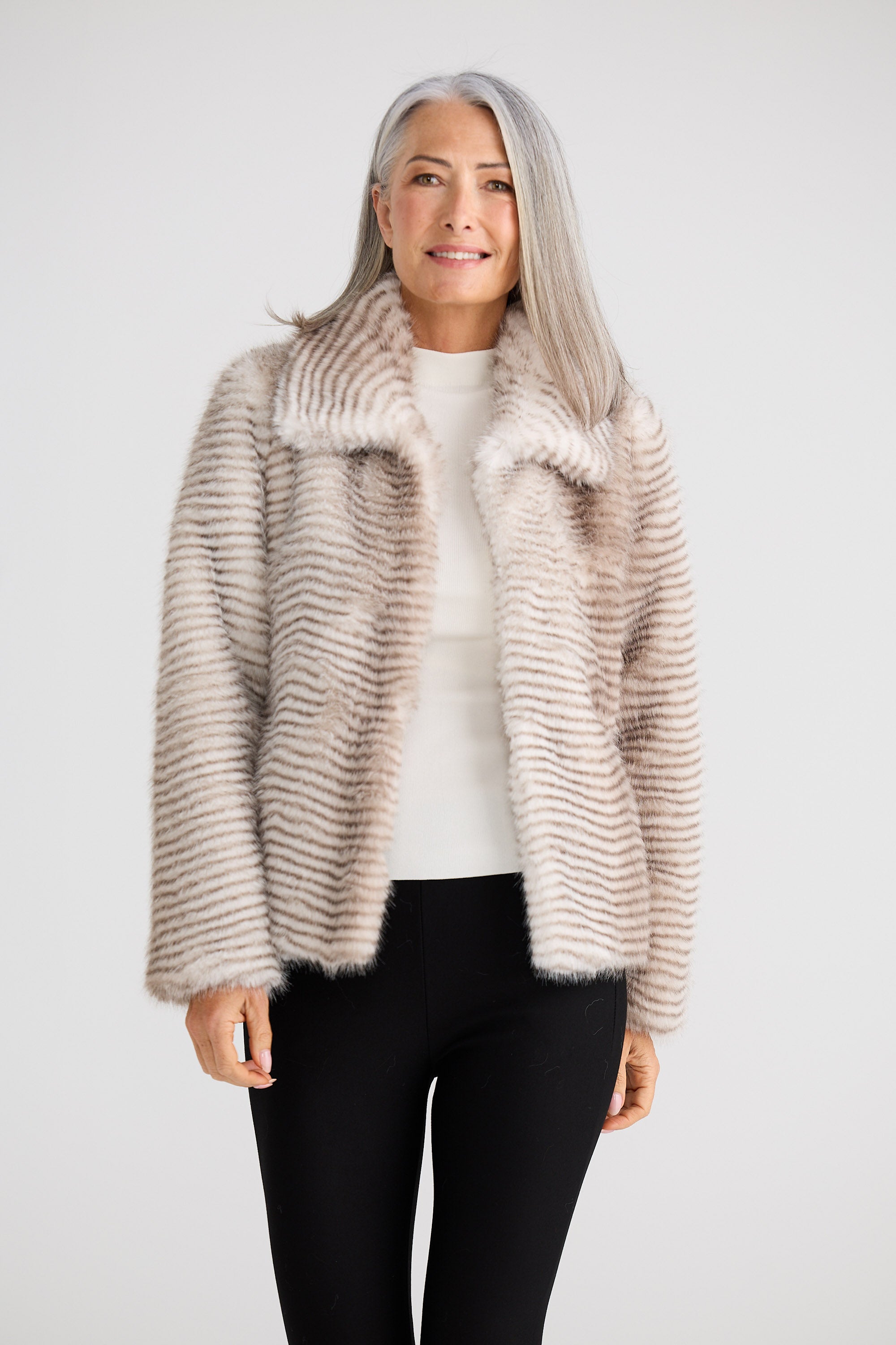 Woman wearing a beige fur coat against a white background