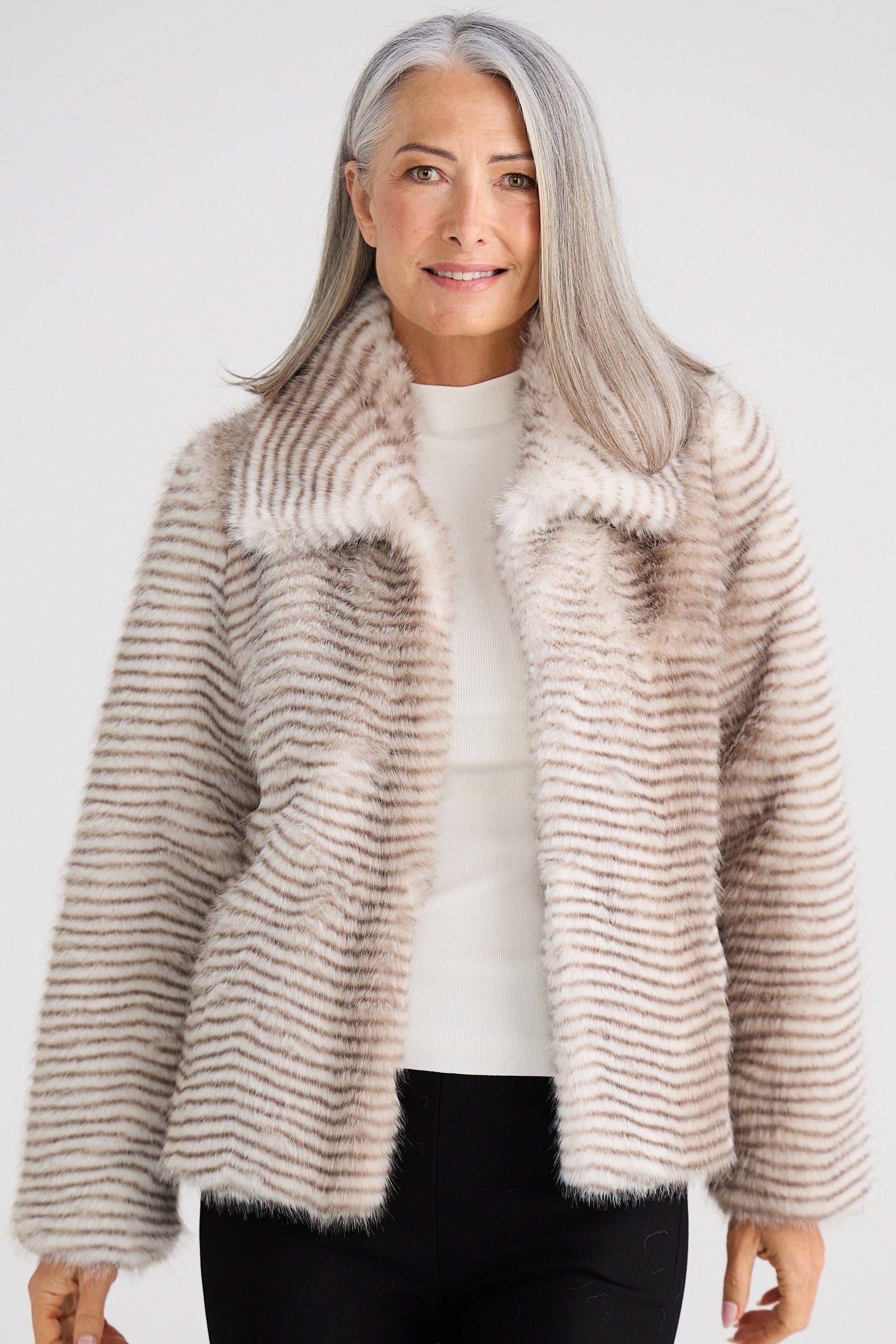 Woman wearing a beige fur coat against a white background