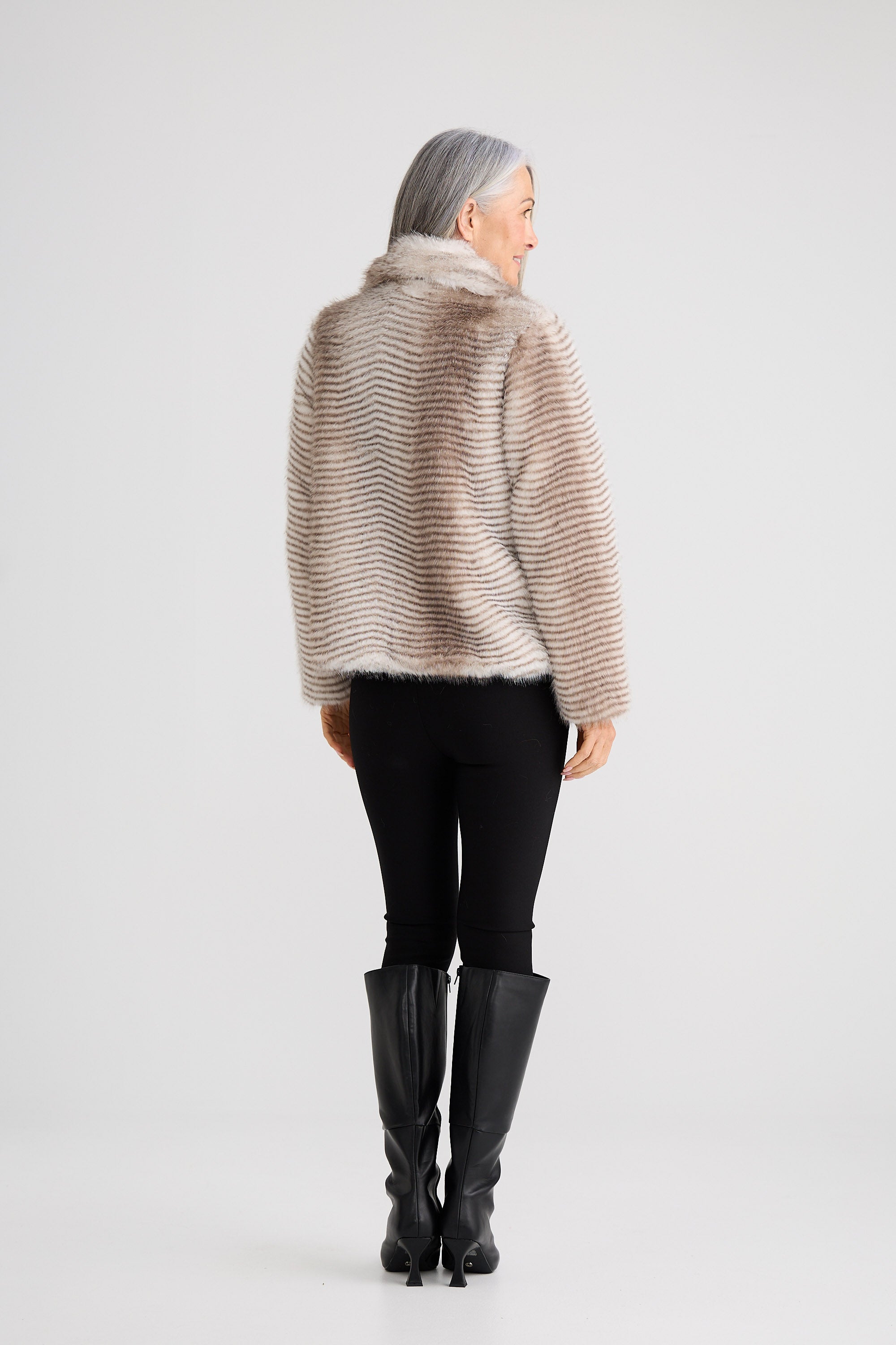 Person wearing a beige sweater and black pants on a white background