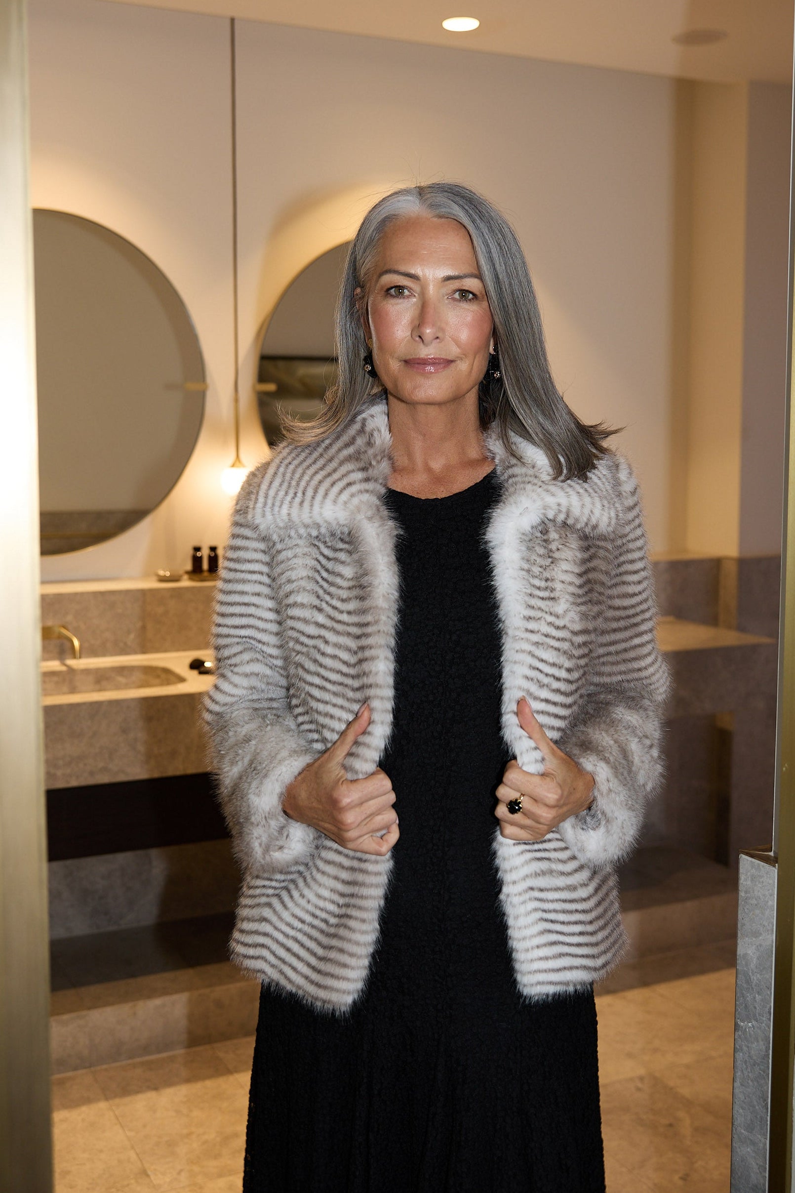 Woman in a fur coat standing in a bathroom